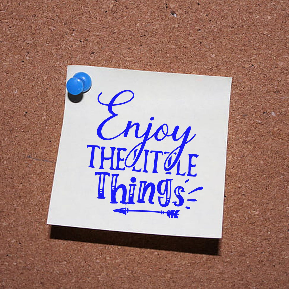 Blue Enjoy the little things stamp and seal design on a white note, pinned with blue pushpins on a corkboard.