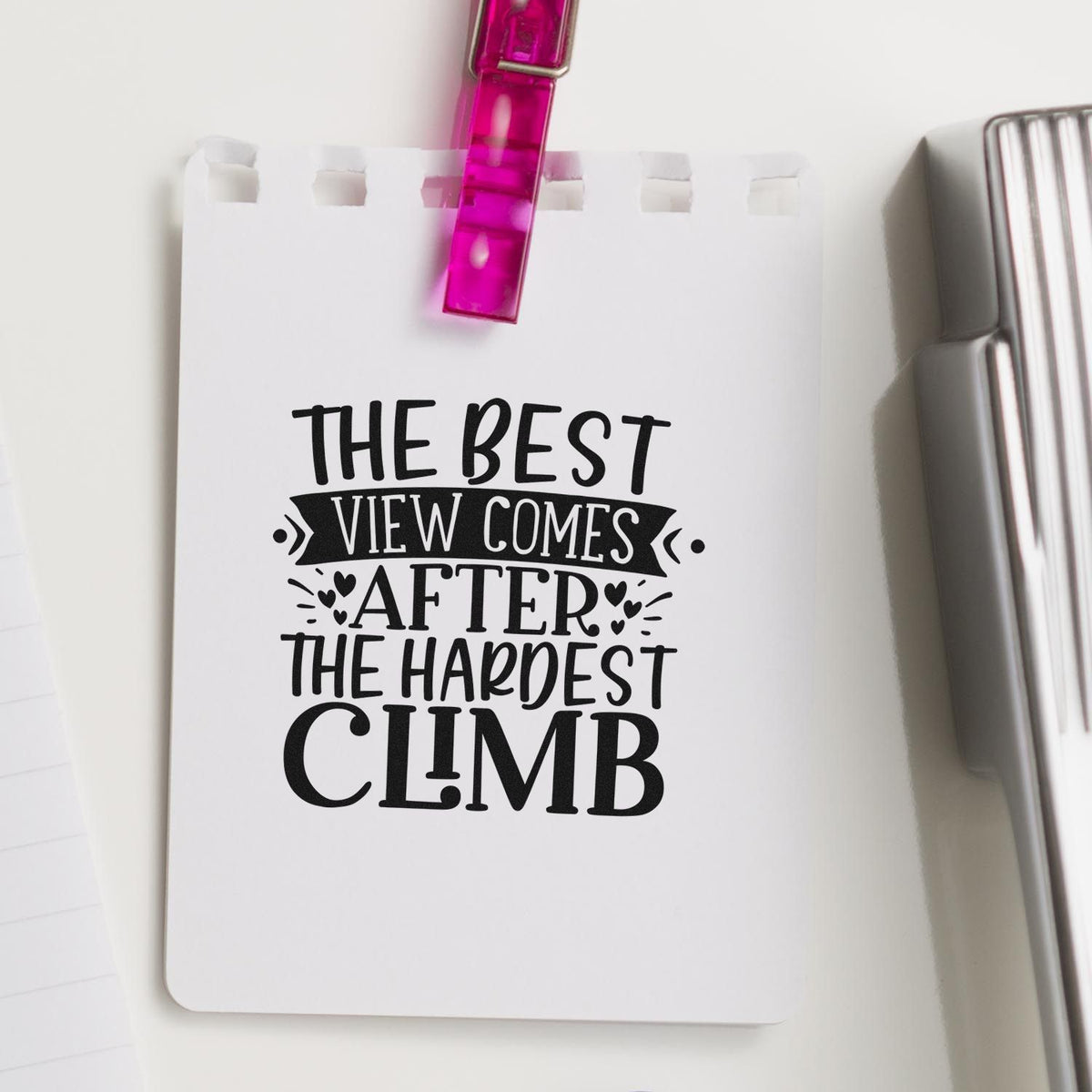 Custom stamp/seal design on white card with black quote, pink clip, and silver stamp tool.