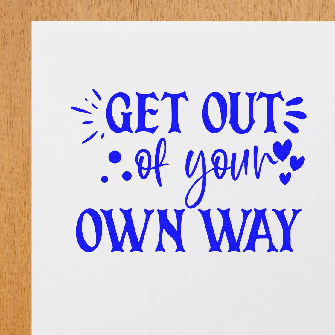 Blue decorative stamp and seal reading Get Out of Your Own Way with hearts on white paper.