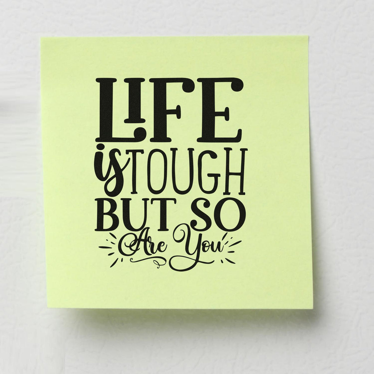 Light green stamp seal with bold black quote, Life is tough but so are you, in decorative typography.