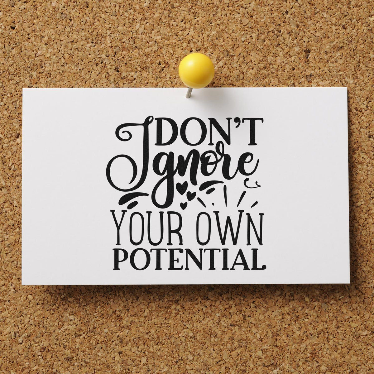 Custom stamp and seal design on white card with black lettering, pinned by yellow tack on corkboard: Dont ignore your own potential.