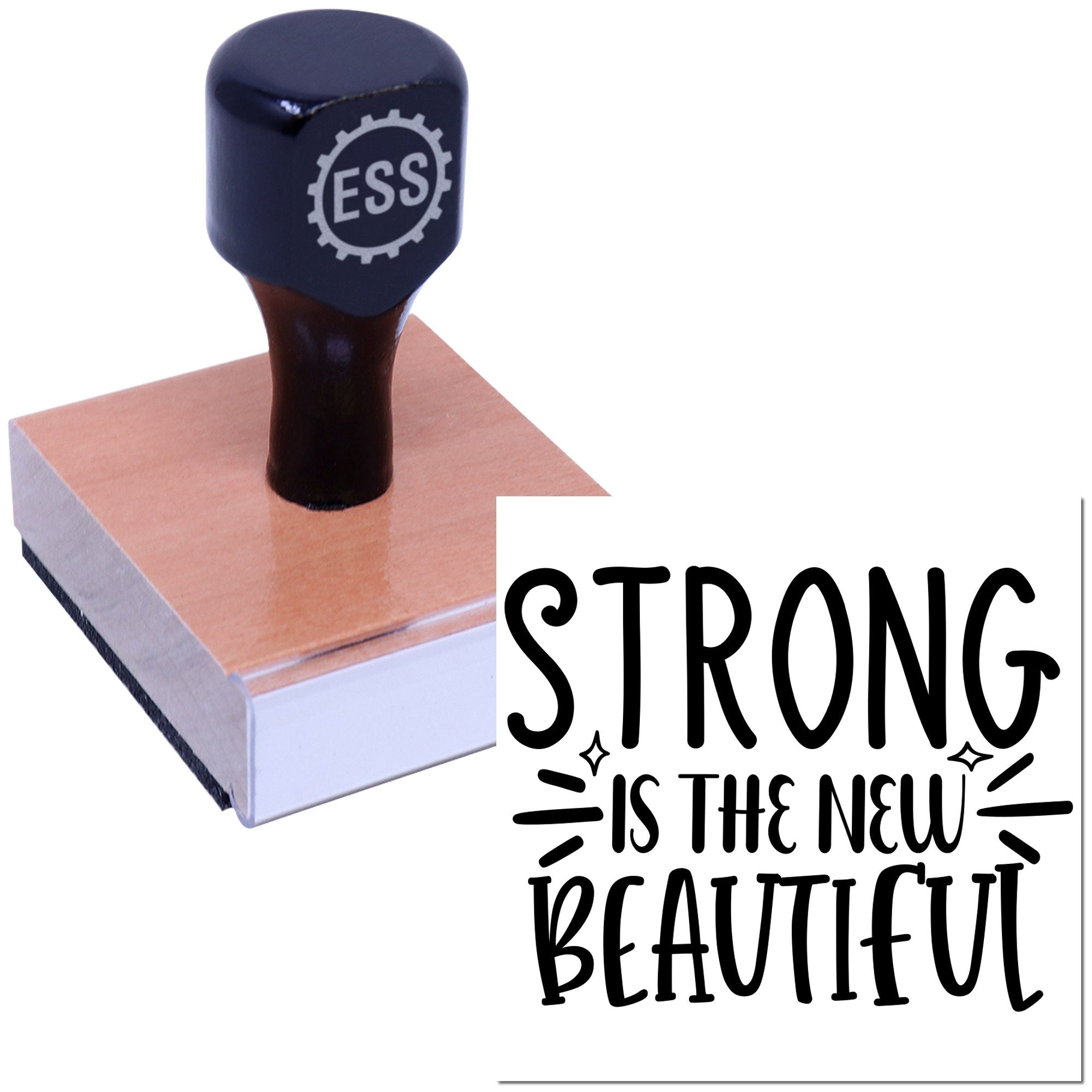 Black ESS seal stamp on a pink wooden block with bold STRONG IS THE NEW BEAUTIFUL text.