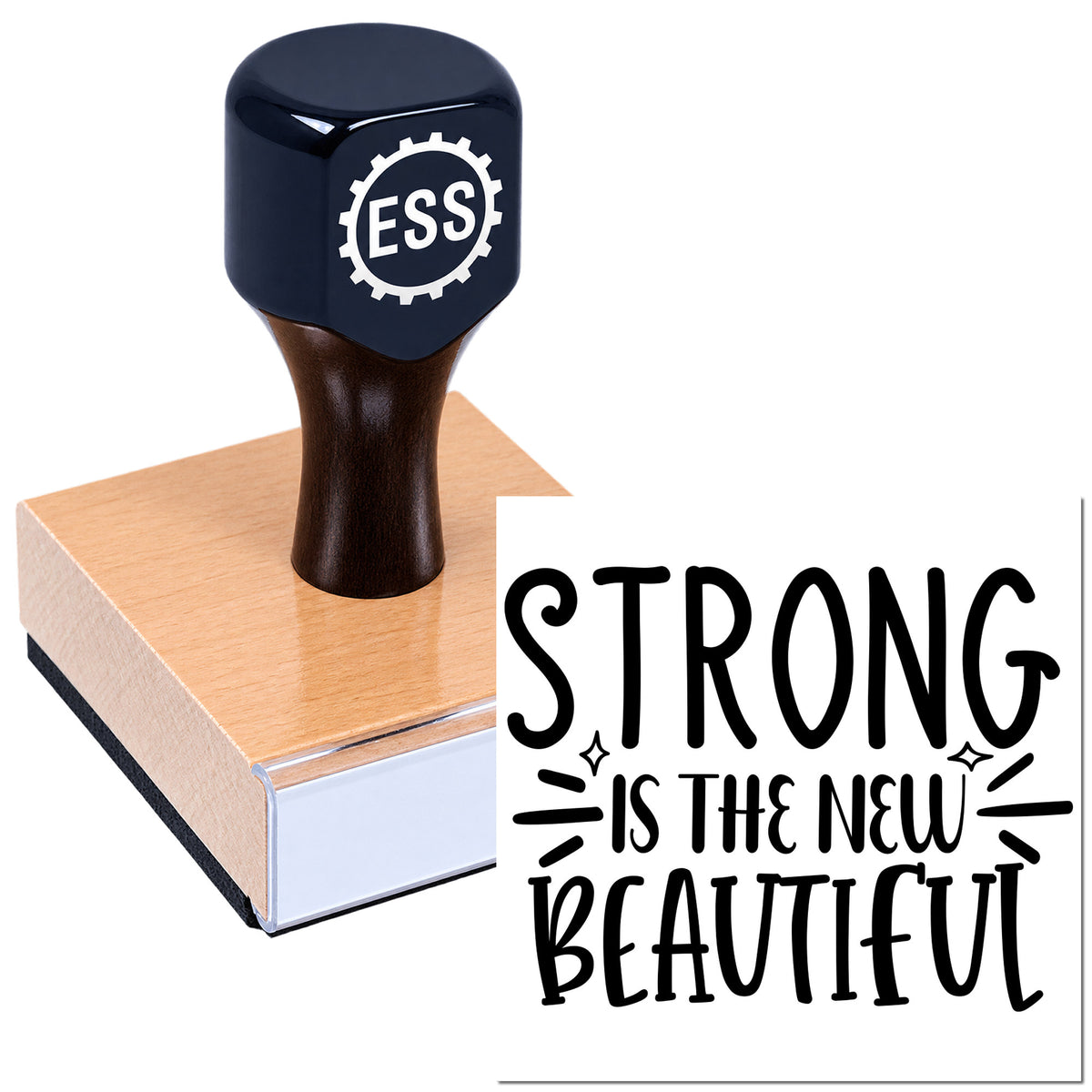 Black ESS seal stamp on a pink wooden block with bold "STRONG IS THE NEW BEAUTIFUL" text.