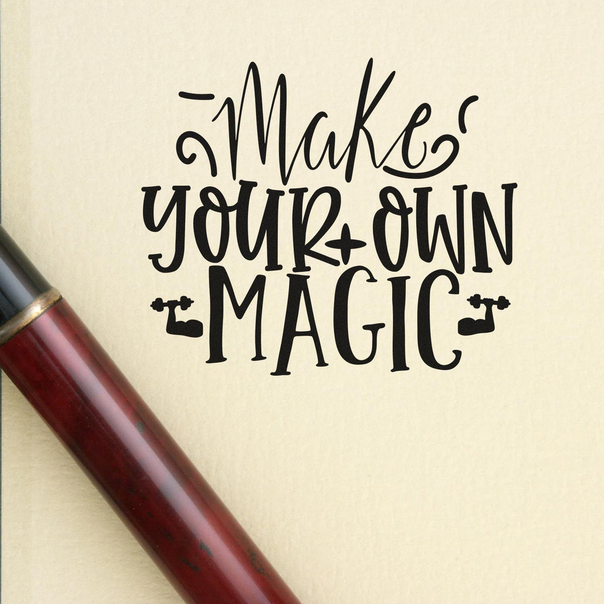 Black rubber stamp and red-handled seal reading Make your own magic on a beige background.