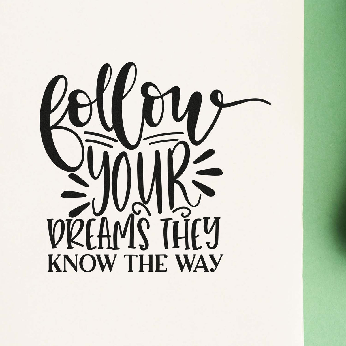 Black custom stamp seal with quote Follow your dreams, they know the way on white paper with green edge.