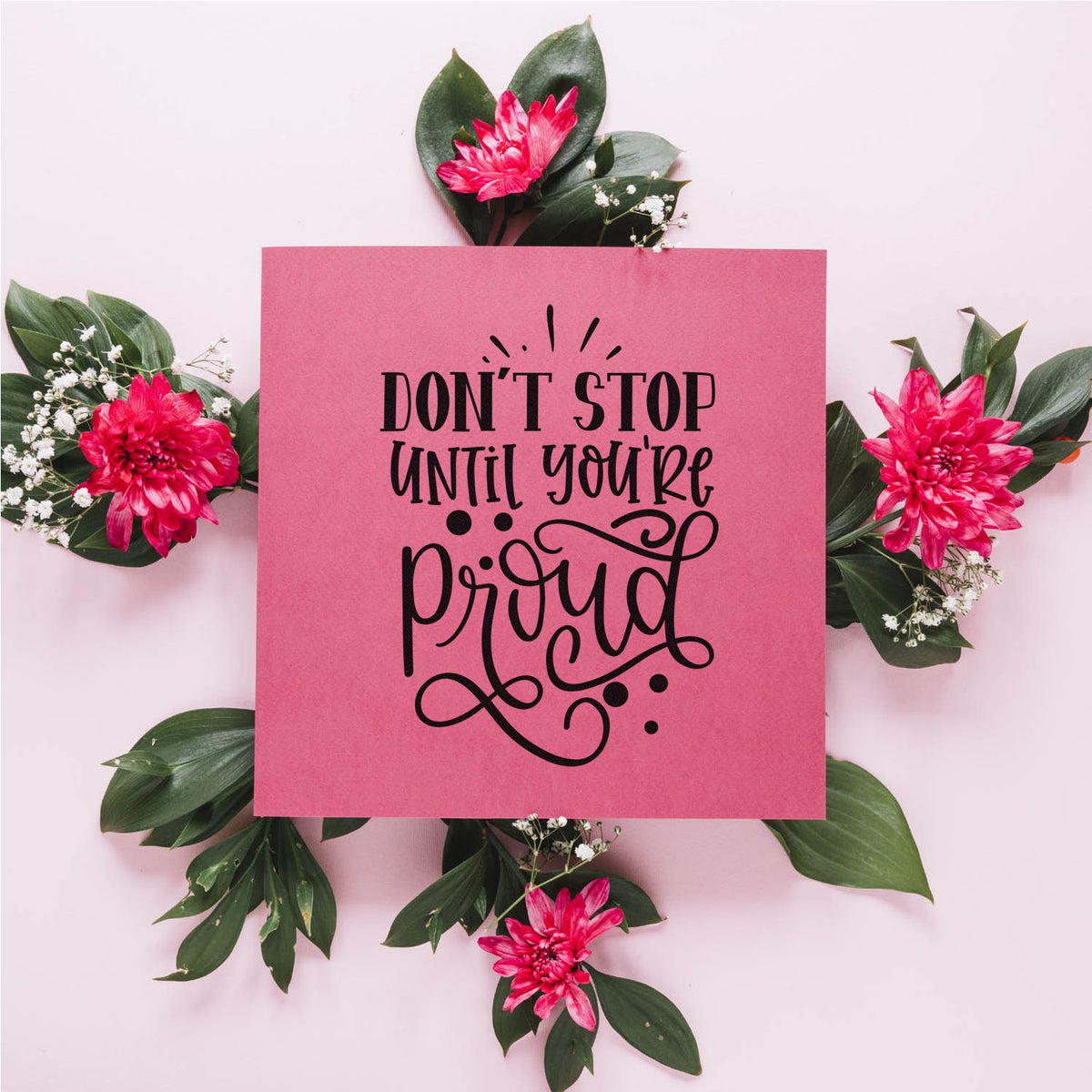 Pink stamp and seal design with black Dont stop until youre proud lettering, green leaves, and bright pink flowers.