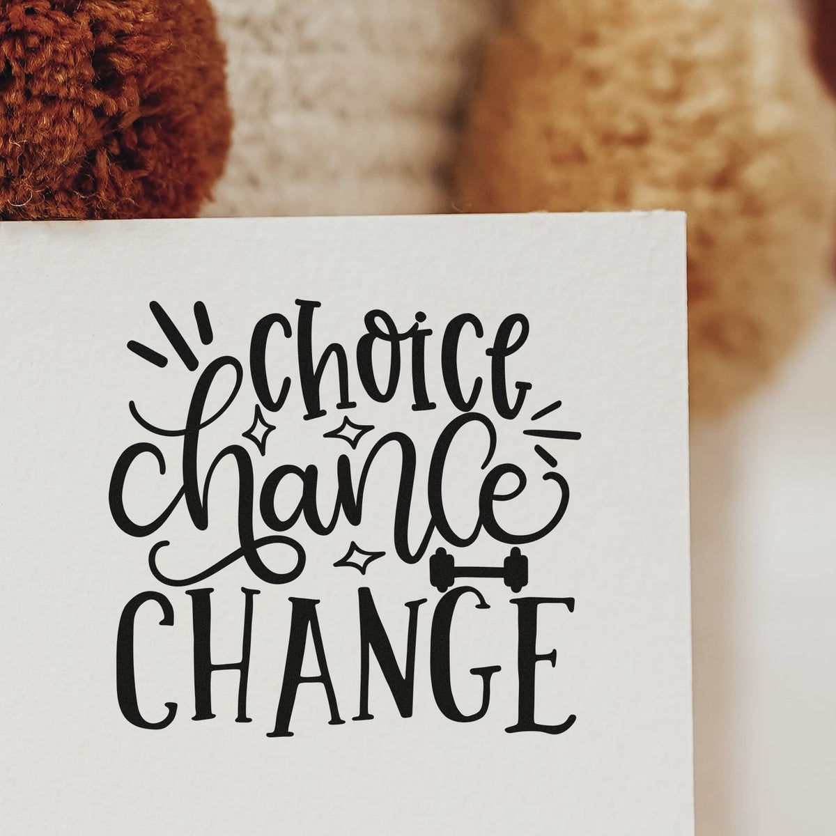 Black decorative stamp and seal design reading choice chance change on white paper, with sparkles and dumbbell icon.