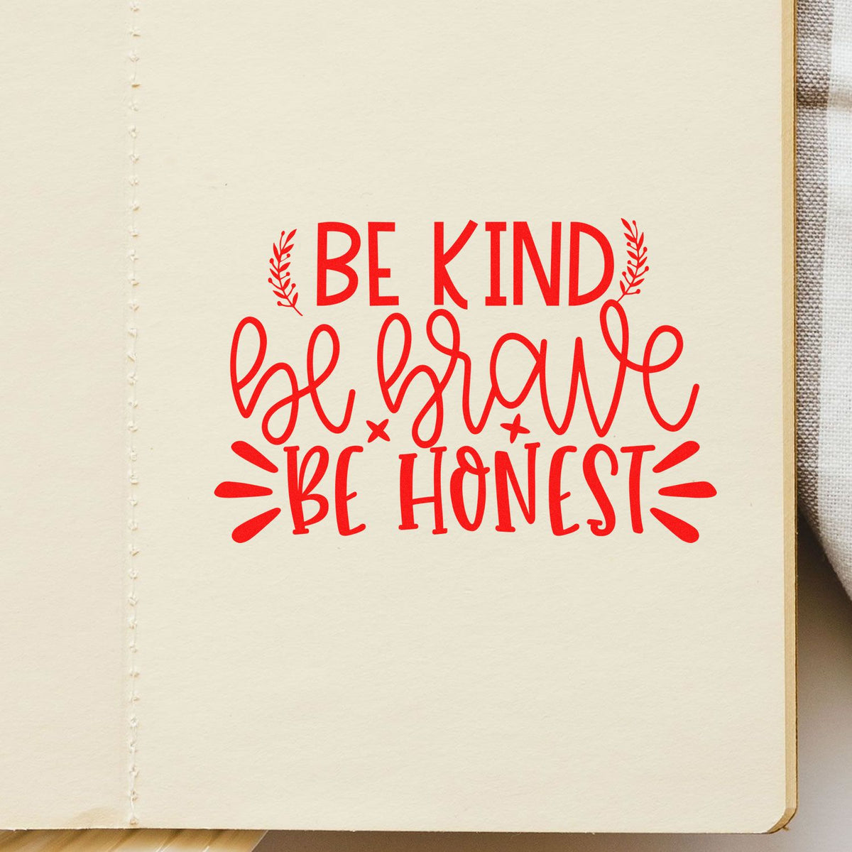 Cream paper page with a red decorative stamp seal reading Be kind, be brave, be honest.