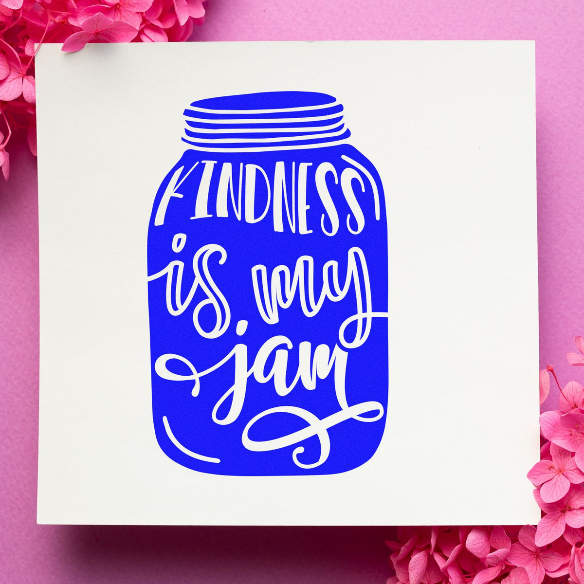 Blue jar-shaped kindness seal stamp on white card, framed by pink flowers.