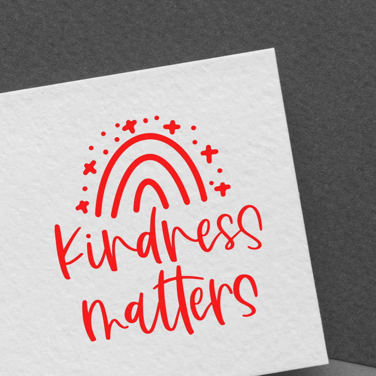 Red Kindness matters stamp seal with rainbow and stars on white paper.