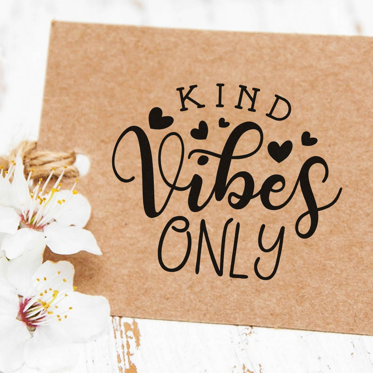 Custom black KIND Vibes Only stamp and seal on brown kraft paper, with heart accents and white blossoms
