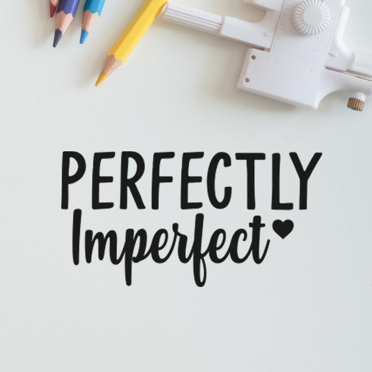 Black Perfectly Imperfect stamp with white seal tool and colored pencils on white background.