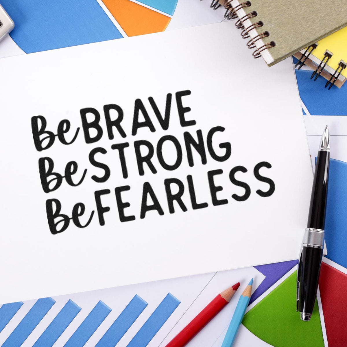 Black stamp impression reading Be Brave, Be Strong, Be Fearless on white paper, framed by colorful stationery and pen.