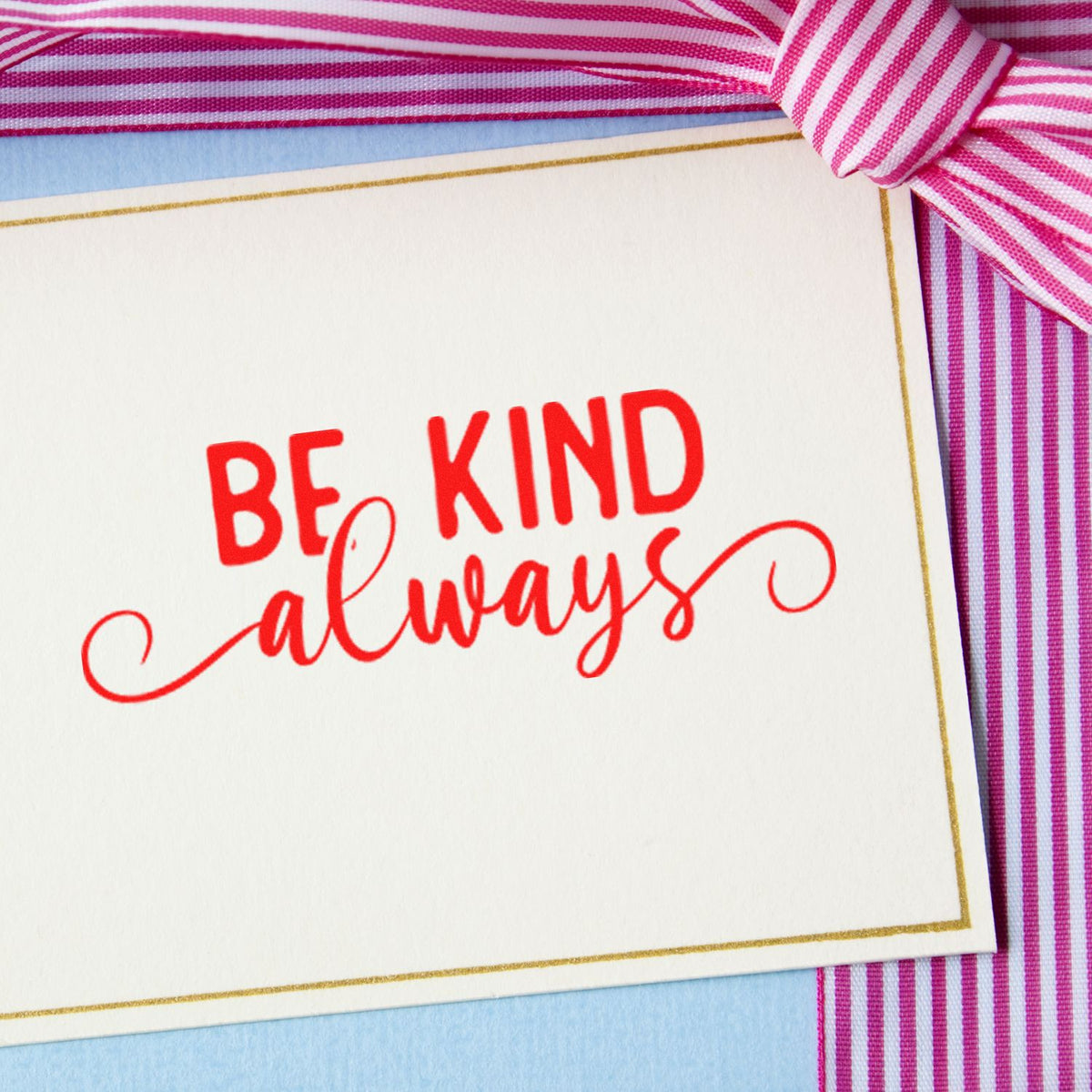 Red Be Kind always stamp on white card with gold border, accented by a pink striped ribbon.