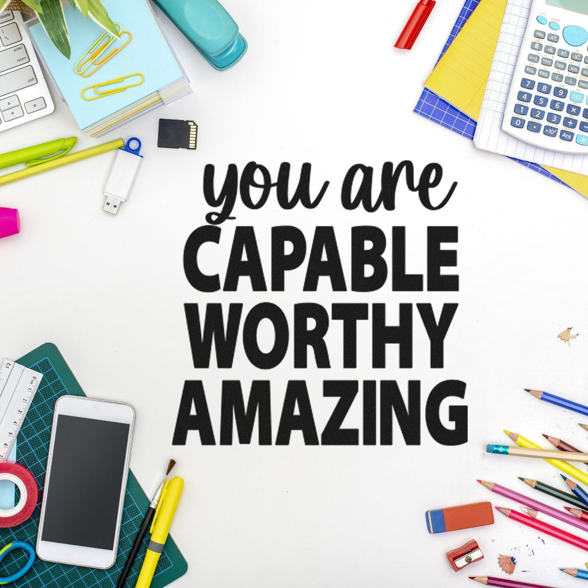 Black motivational stamp and seal reading you are capable worthy amazing, framed by colorful stationery on a white background.
