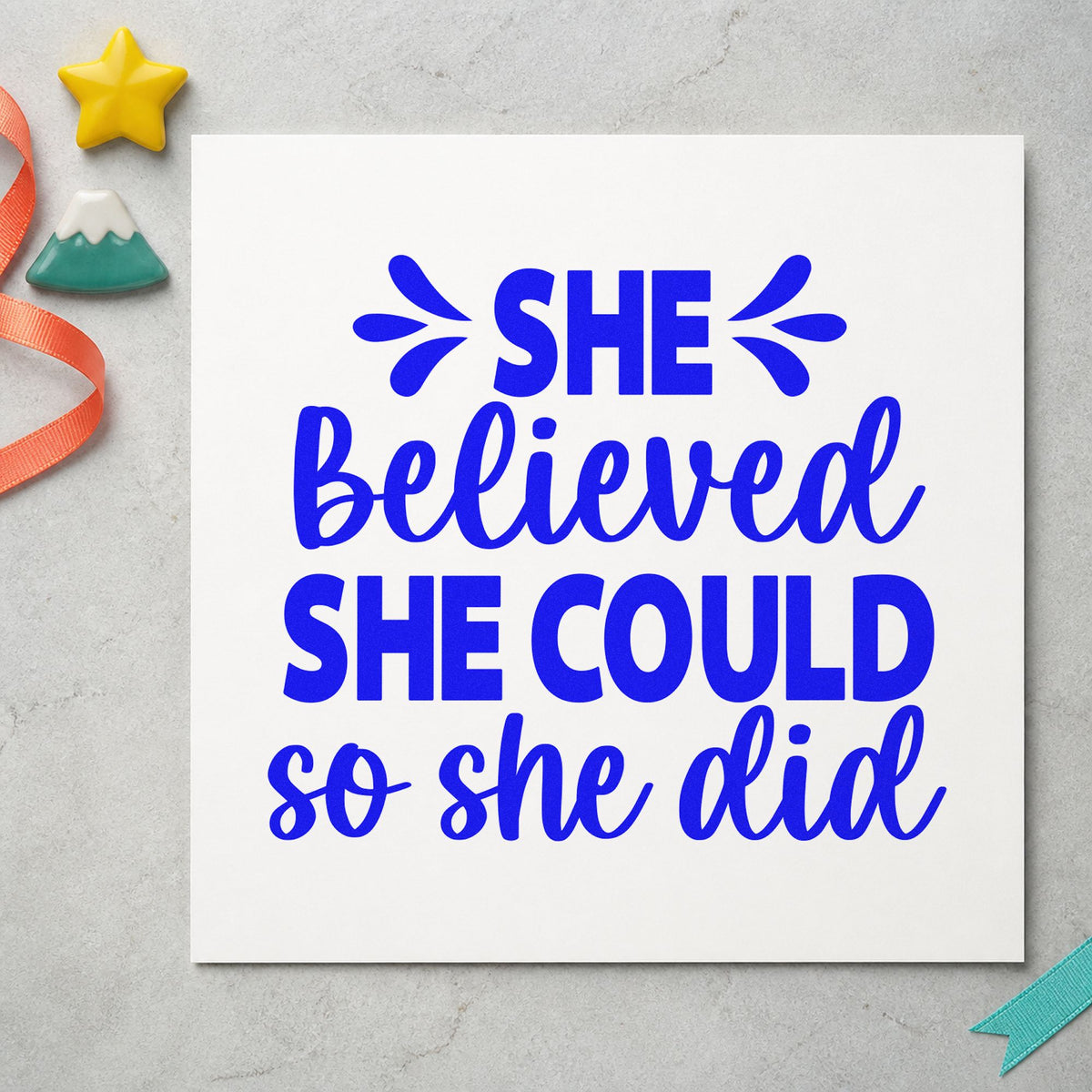 She Believed She Could craft stamp imprinted in blue ink on paper, a design suited to framed meeting space.