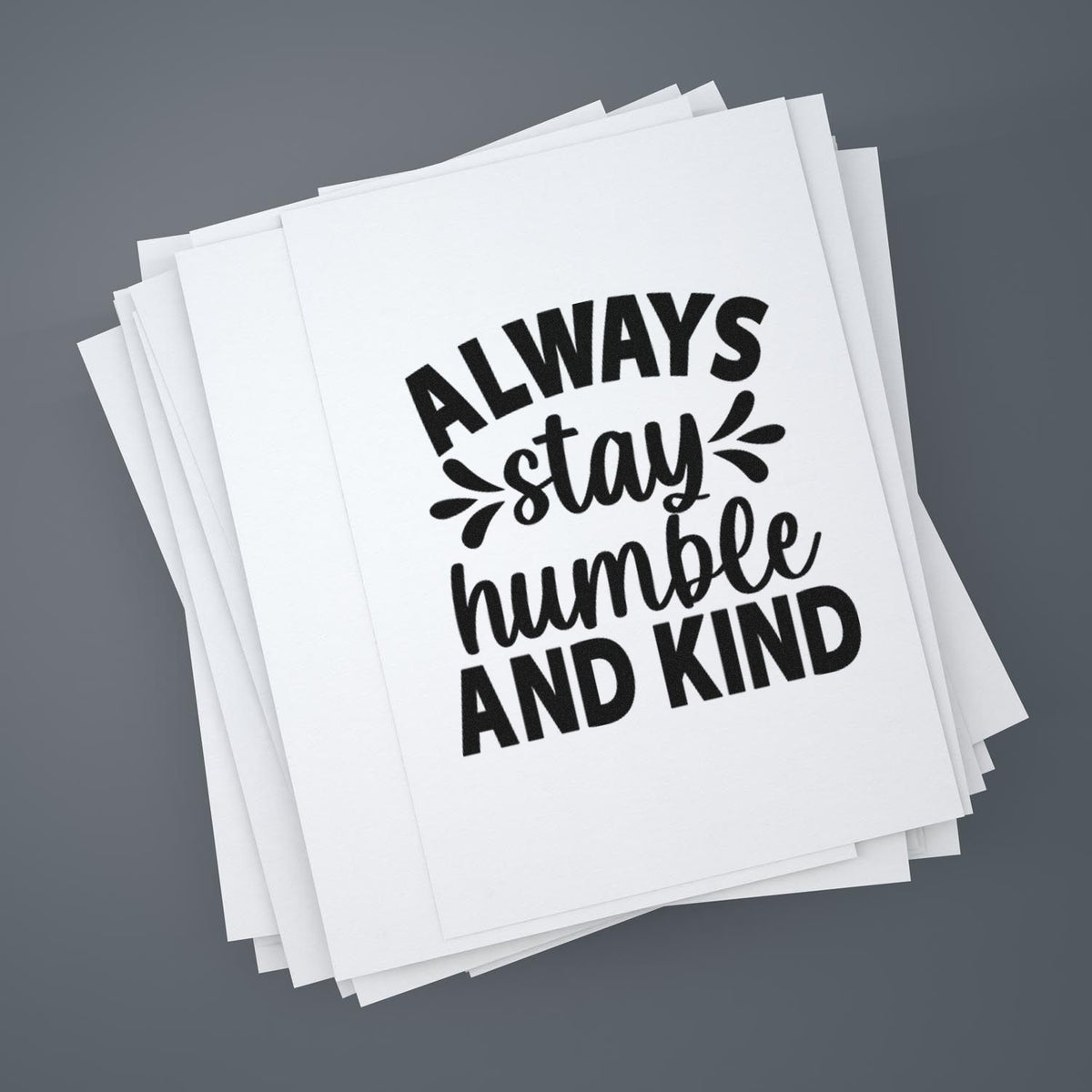 Stacked white stamp and seal sheets with black Always stay humble and kind lettering on a gray background.