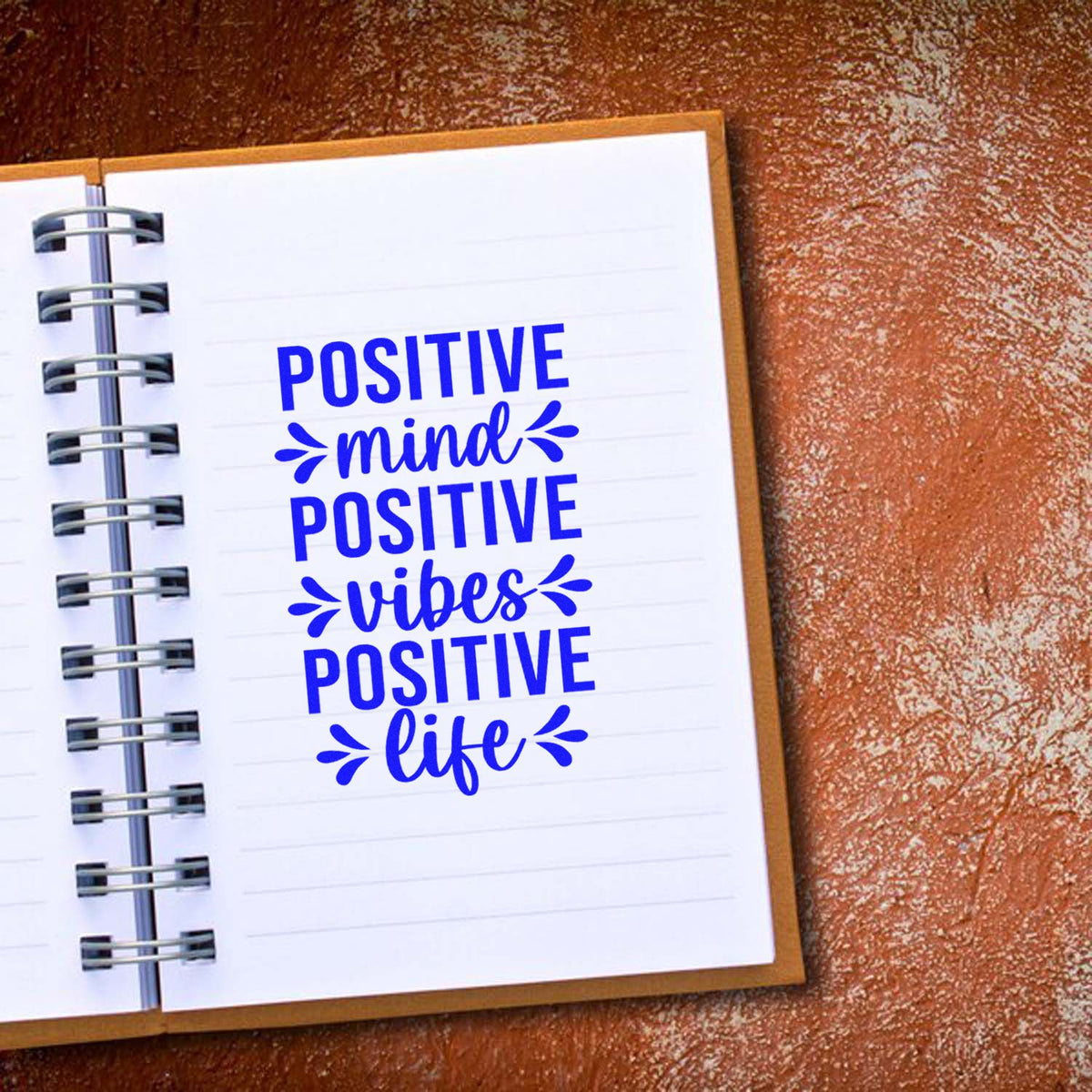 Blue motivational stamp/seal design on a spiral notebook: Positive mind, positive vibes, positive life in bold blue.