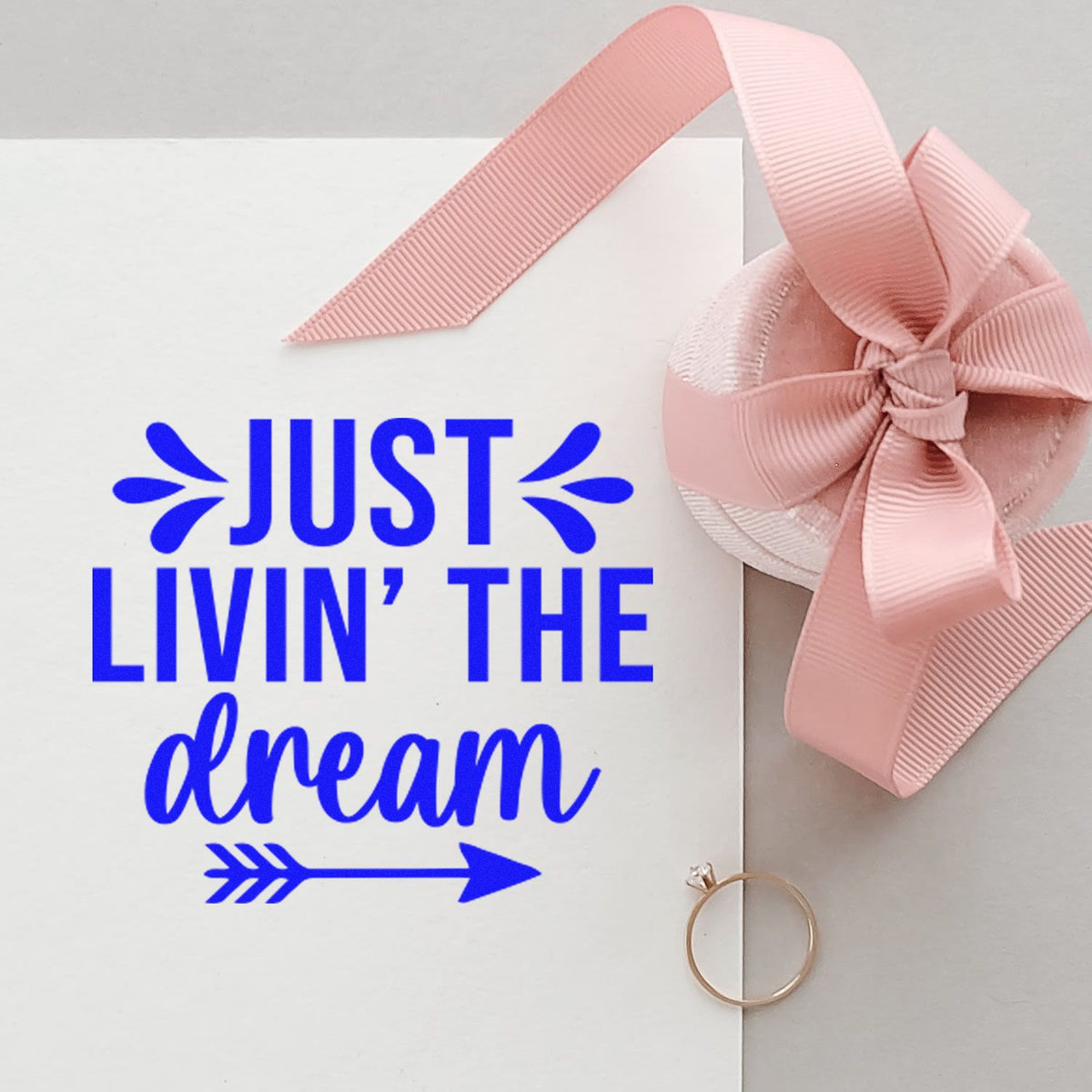 Blue Just Livin the dream stamp with pink ribbon seal and gold ring on white card