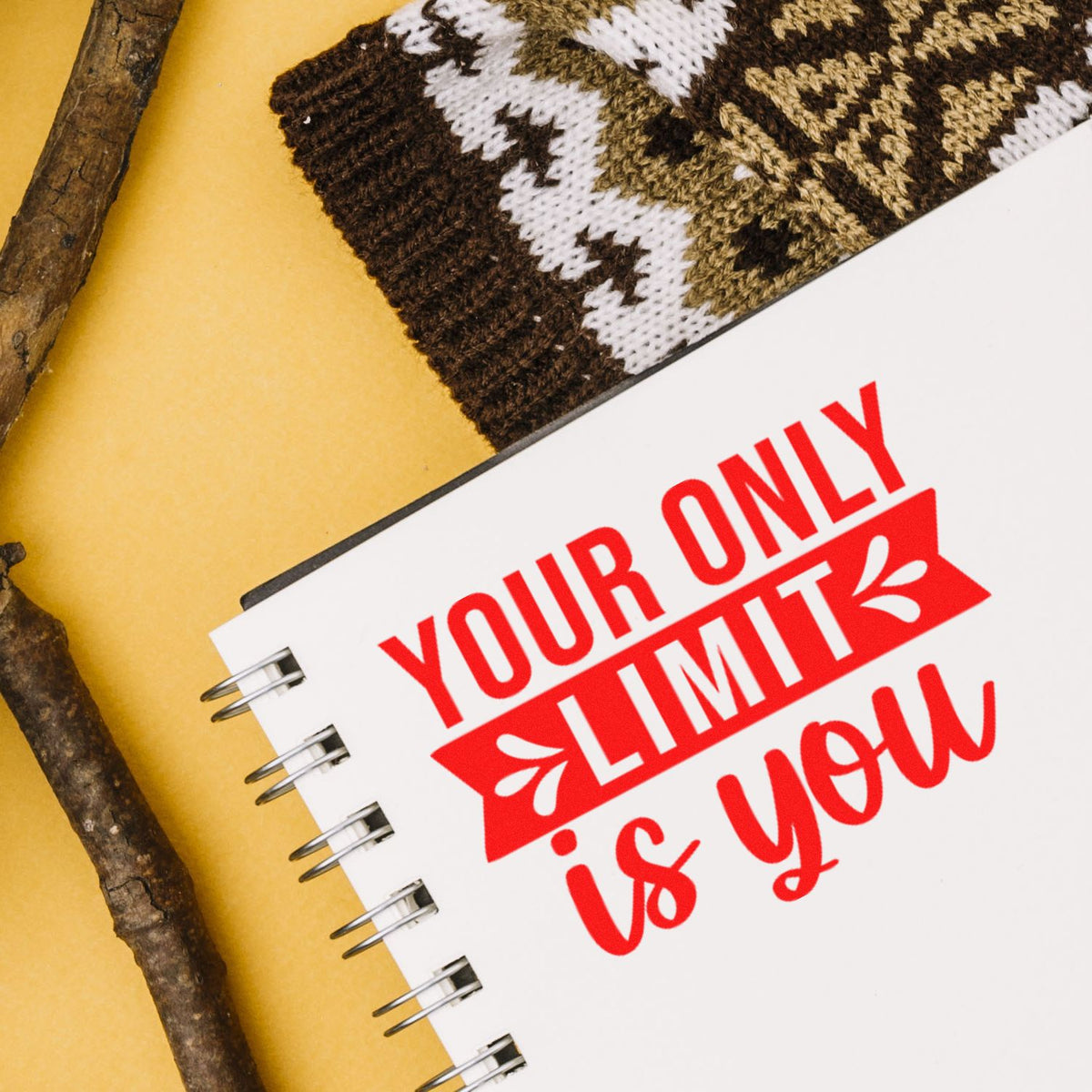 Red custom stamp and seal design reading Your only limit is you on a white spiral notebook over a yellow background.
