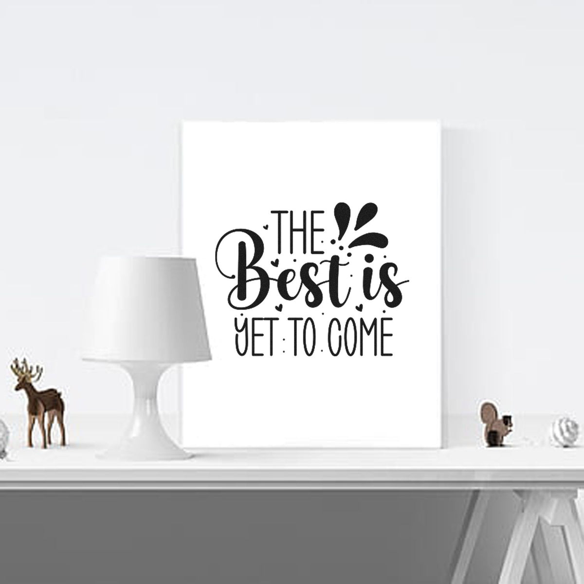 Black calligraphy stamp and seal design with The Best Is Yet To Come text on a white background and decorative splashes.