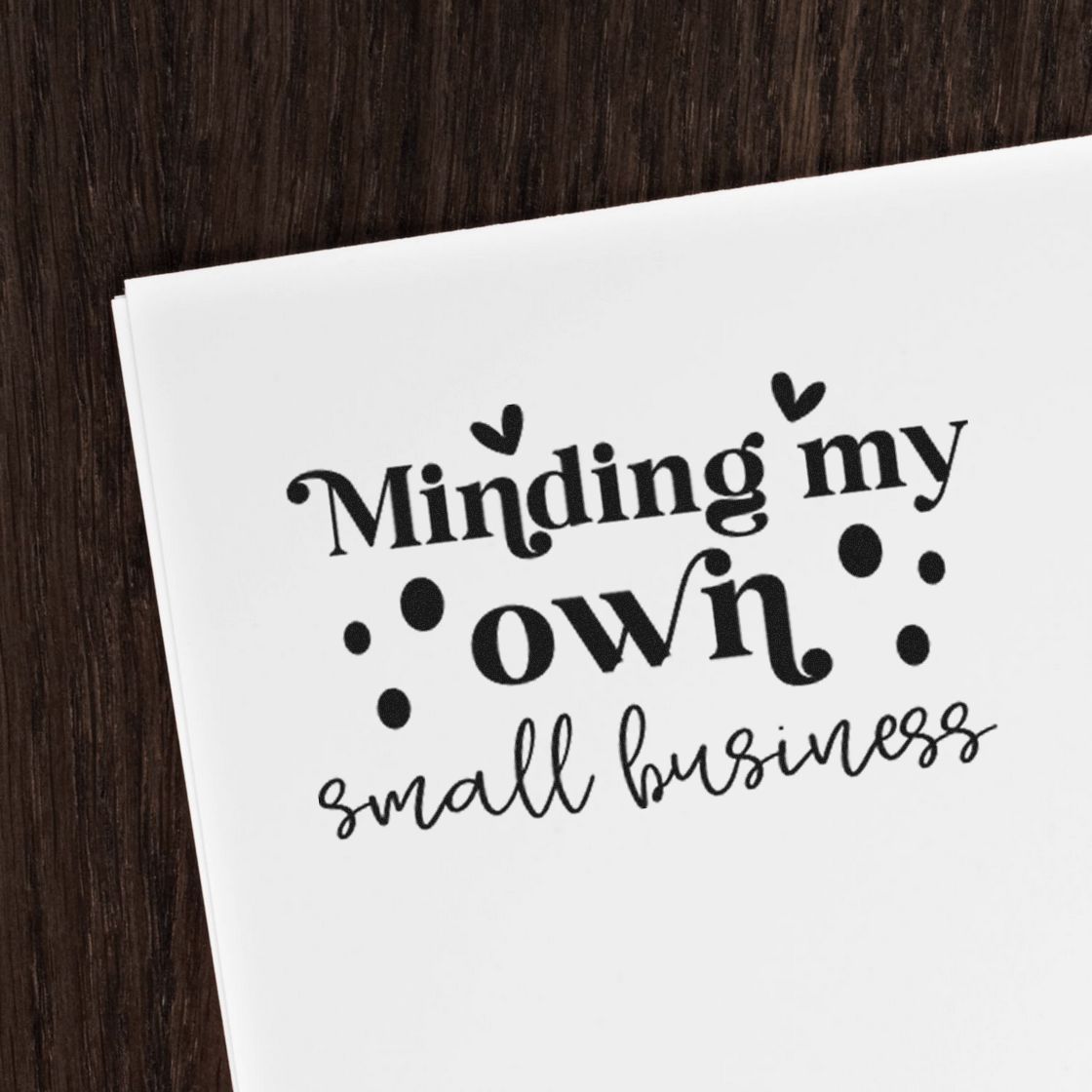 Black custom stamp and seal design reading Minding my own small business on white paper with hearts and dots.