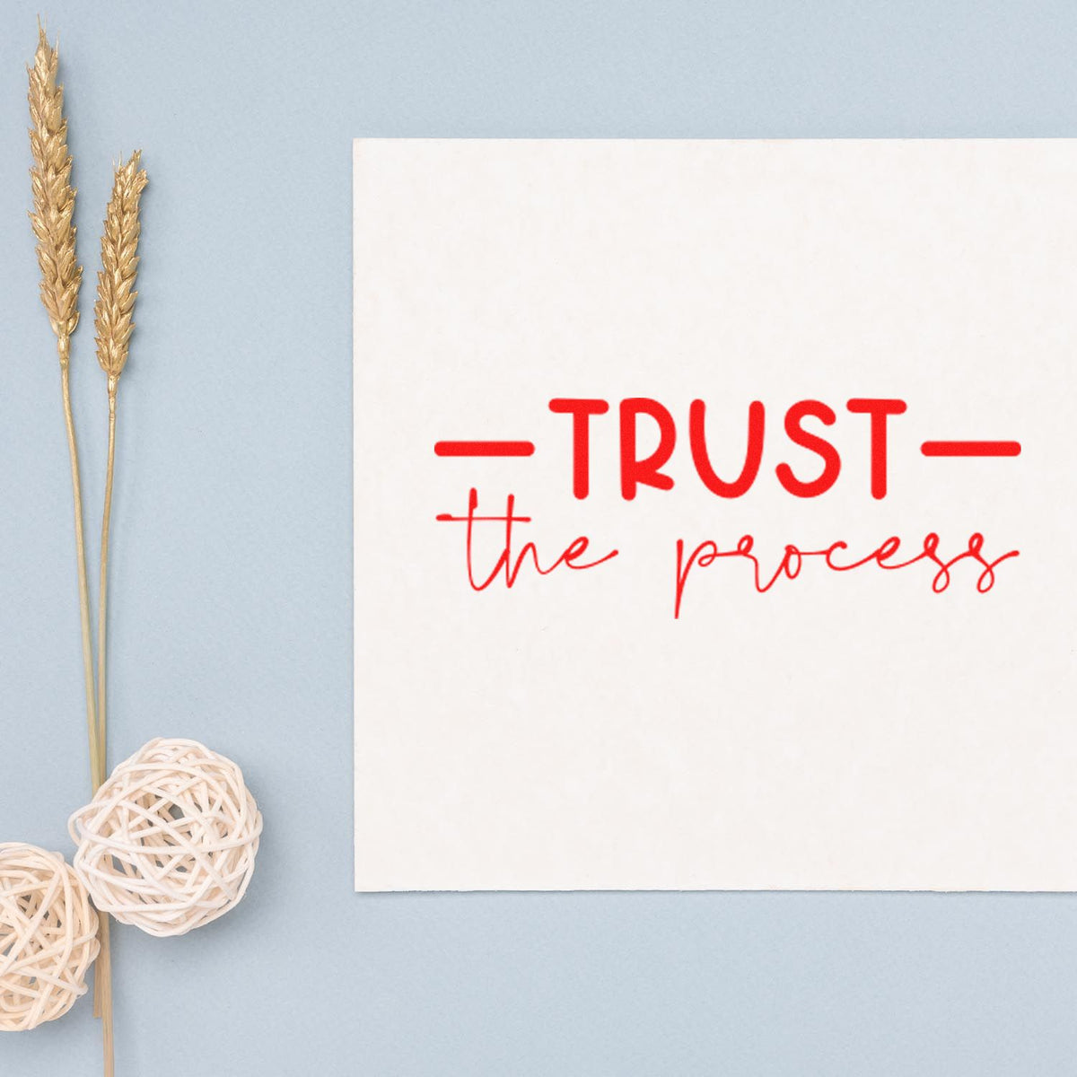 Custom stamp and seal design: red TRUST the process on white card, with gold wheat stems and white woven accents on pale blue.