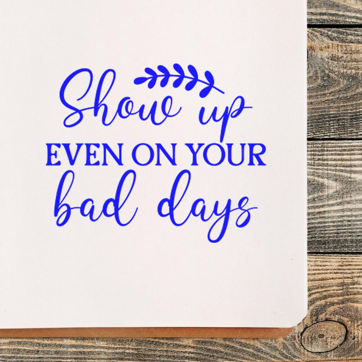 Blue custom stamp seal with leaf accent reading Show up even on your bad days on white paper.