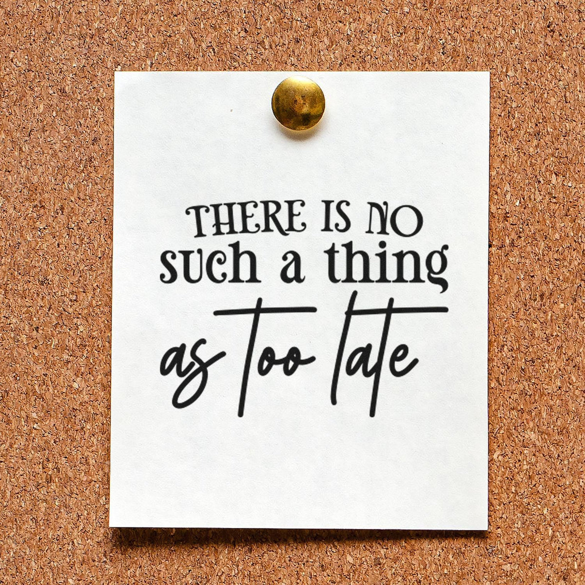 Black custom stamp on white card pinned to corkboard with brass tack; reads There is no such thing as too late.
