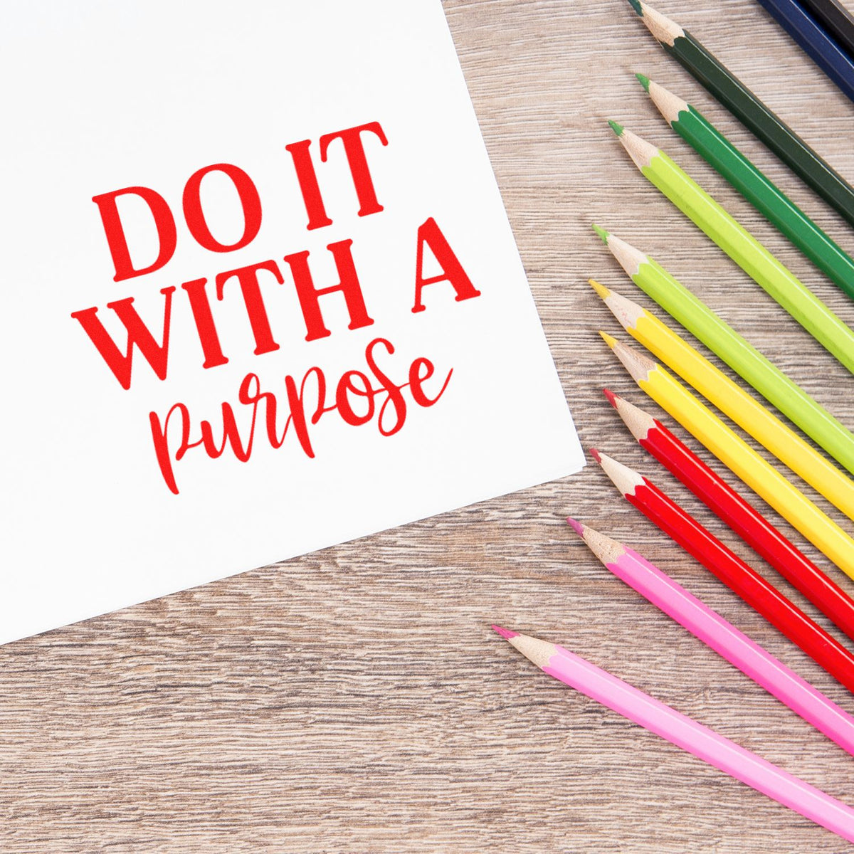 Custom stamp and seal design with red Do It With a Purpose text beside colorful pencils on a wood desk.