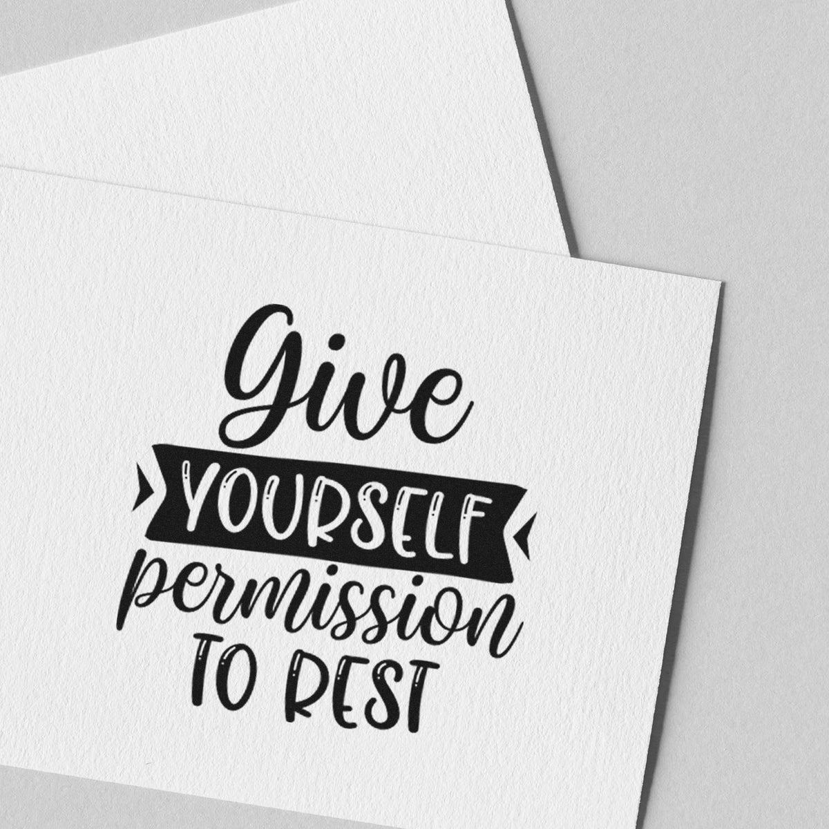 Black stamp-style seal on white textured card reads Give yourself permission to rest.