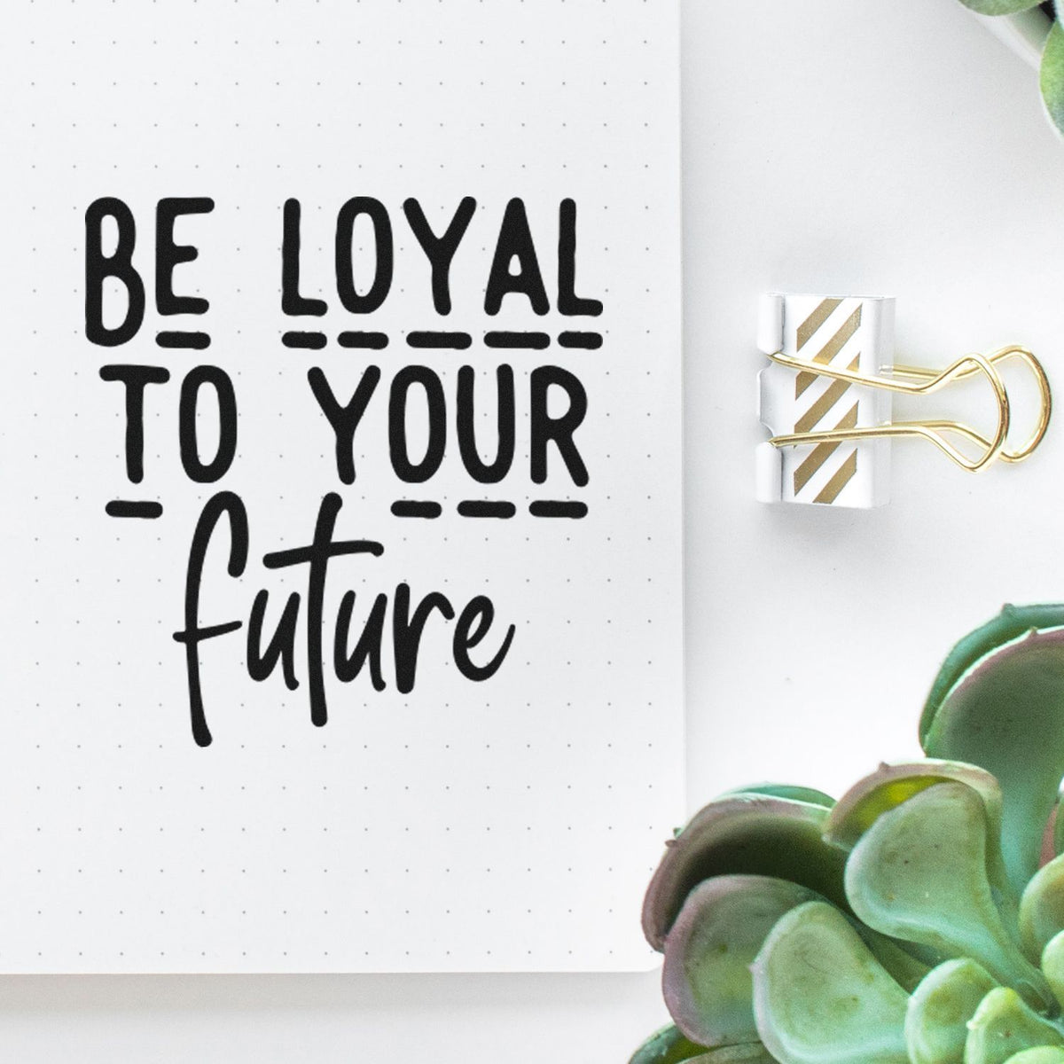 Custom stamp and seal reading Be loyal to your future in black on white dotted paper, clipped with a gold-striped binder clip.