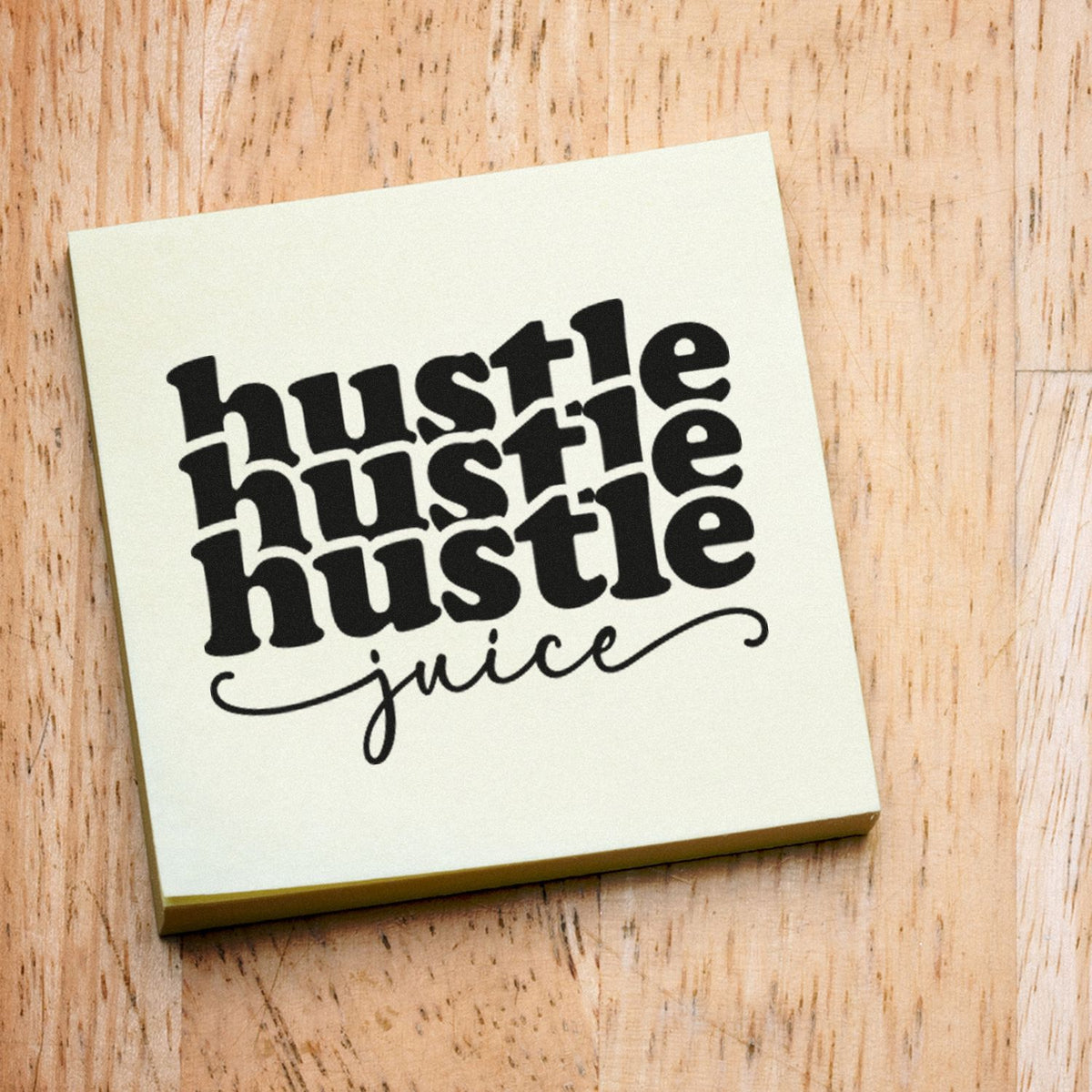 Cream square stamp and seal with black hustle hustle hustle juice text on a light wood background.