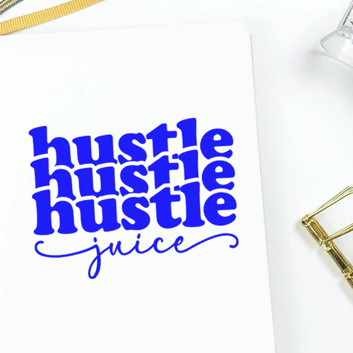 Blue hustle hustle hustle juice stamp on white paper with gold accents and binder clip, showcasing a seal product.