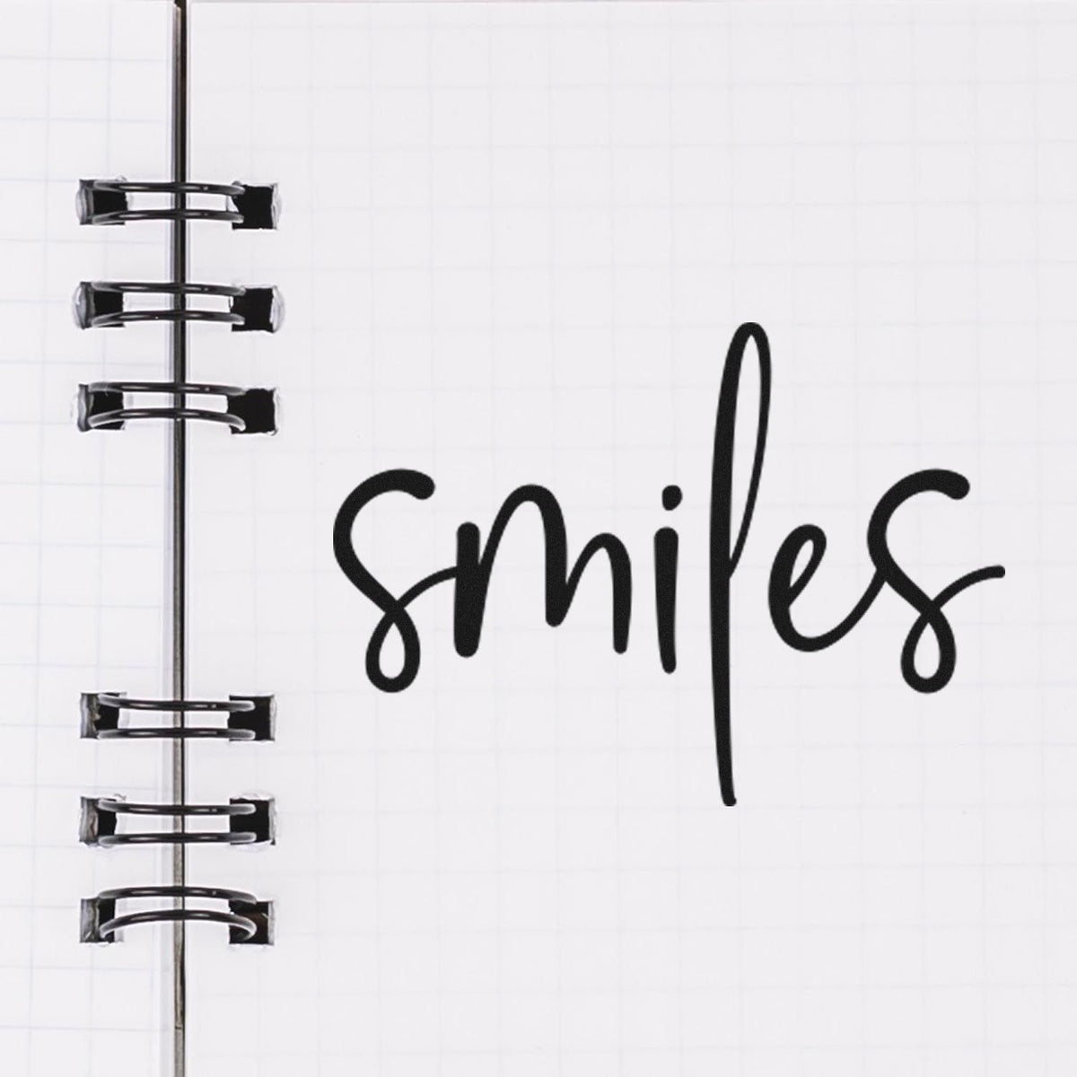 Black spiral-bound stamp and seal product with smiles in bold black script on white grid paper.
