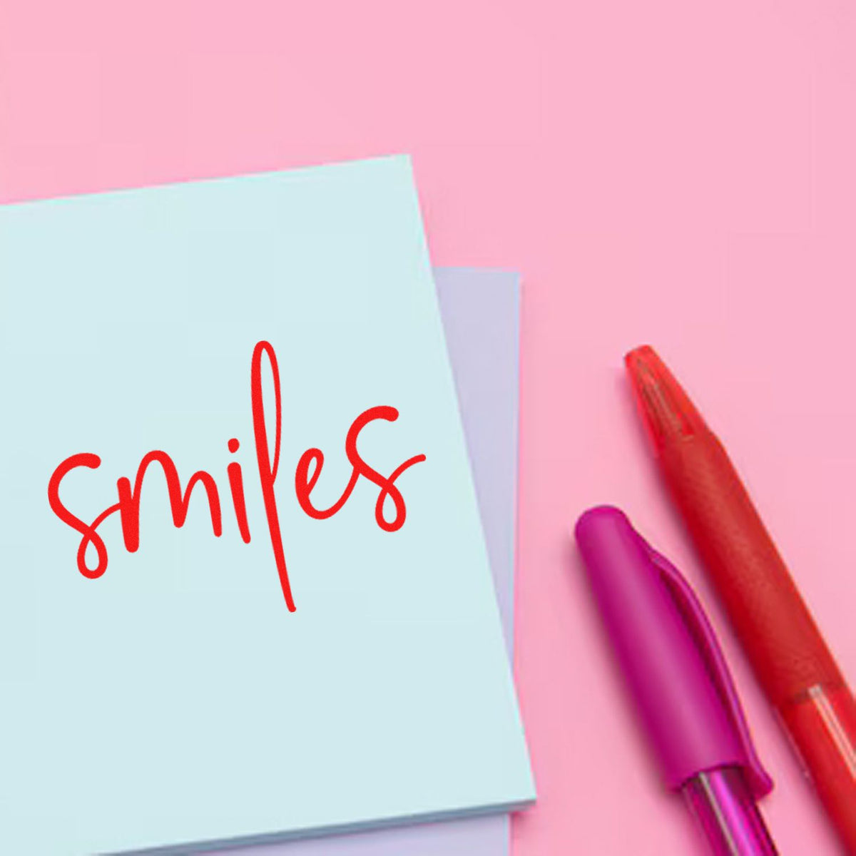 Pink background with blue and lavender stamp pads, red smile seal impression, and red and purple stamp handles.