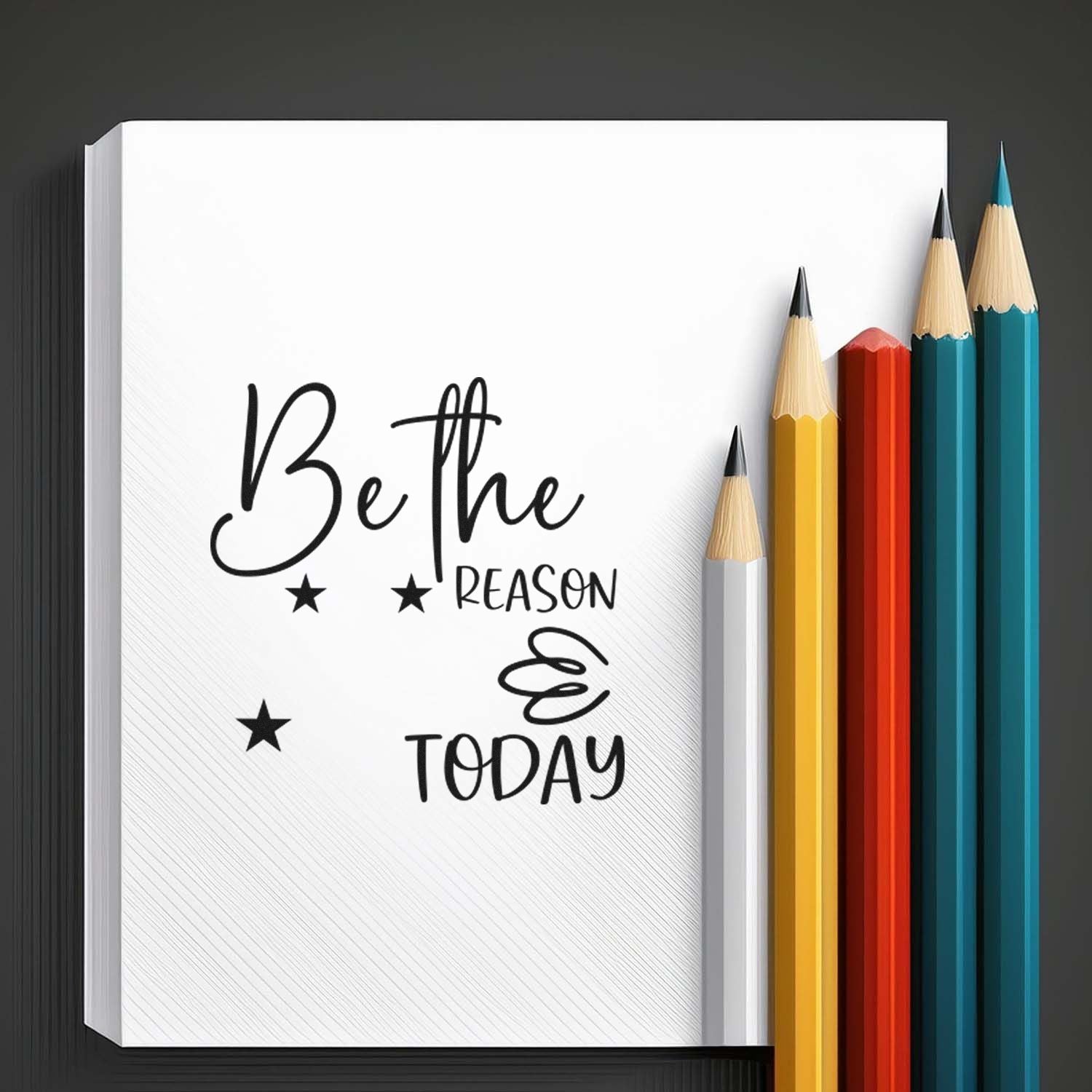 Custom stamp and seal product with white notebook, black Be the reason today text, stars, and colorful pencils.