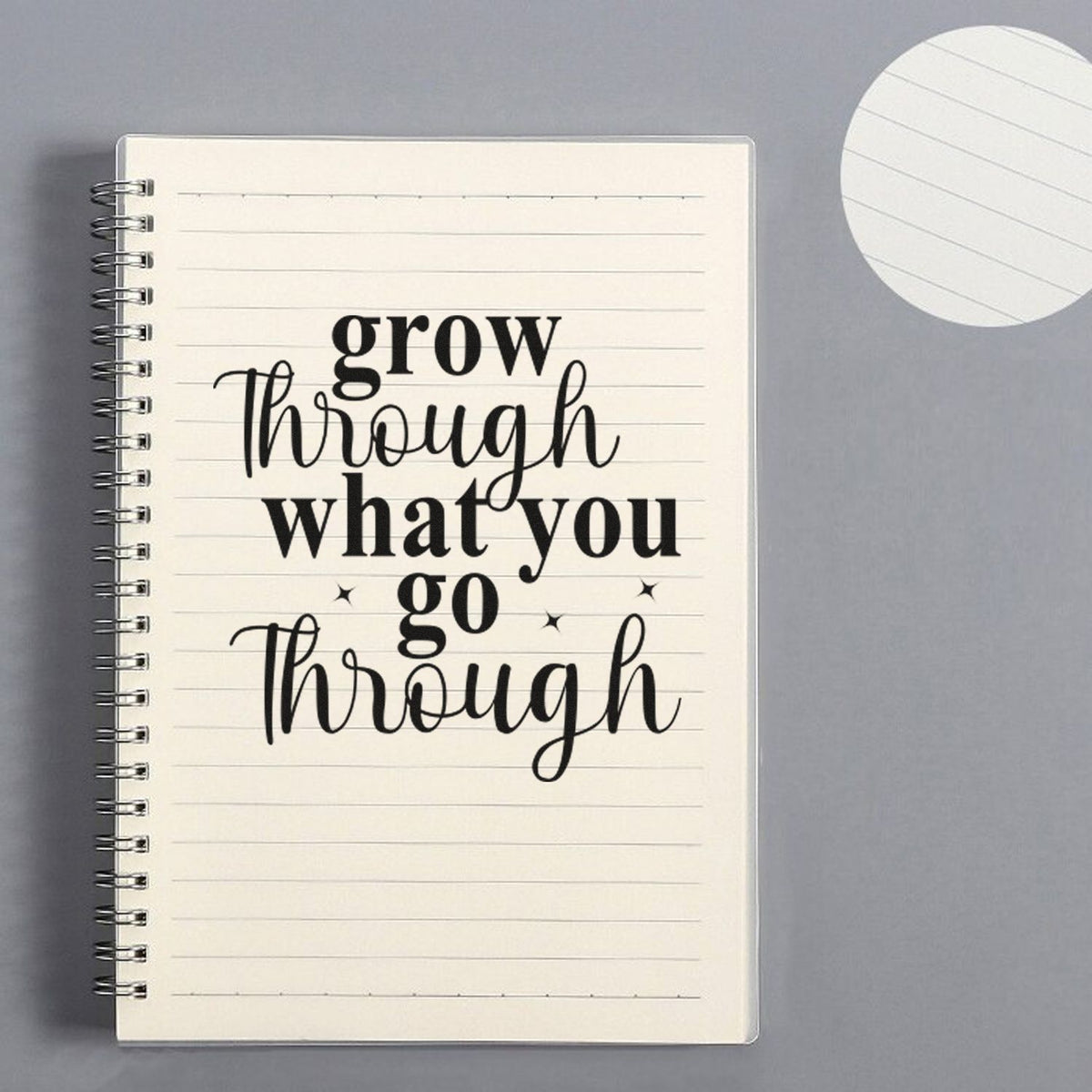 Black quote stamp on lined notebook page with spiral binding, beside a white round seal stamp on gray background.