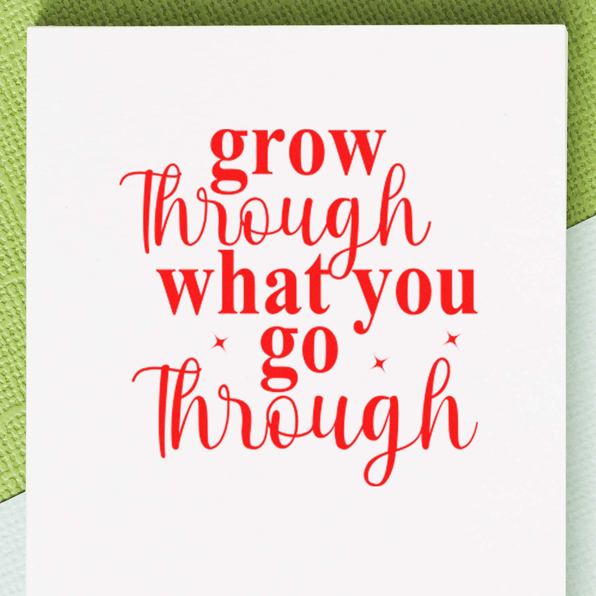 Red stamp-seal quote grow through what you go through on a white card with small stars, green textured background.