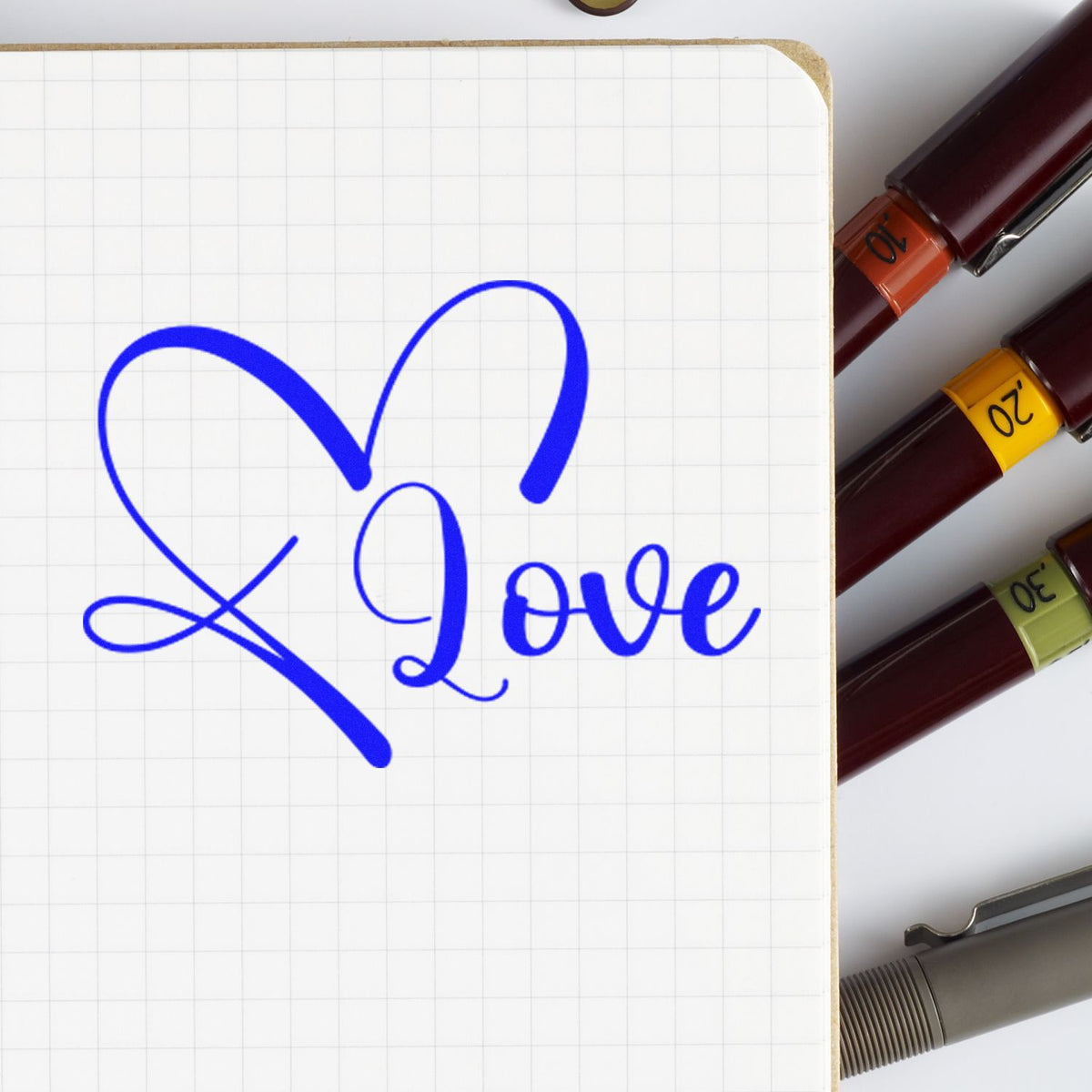 Blue heart and Love stamp on graph paper notebook, with burgundy stamp and seal markers with numbered color bands.