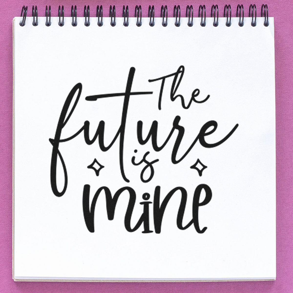 Black calligraphy stamp/seal reading The future is mine on a white spiral notebook page, with a purple background.