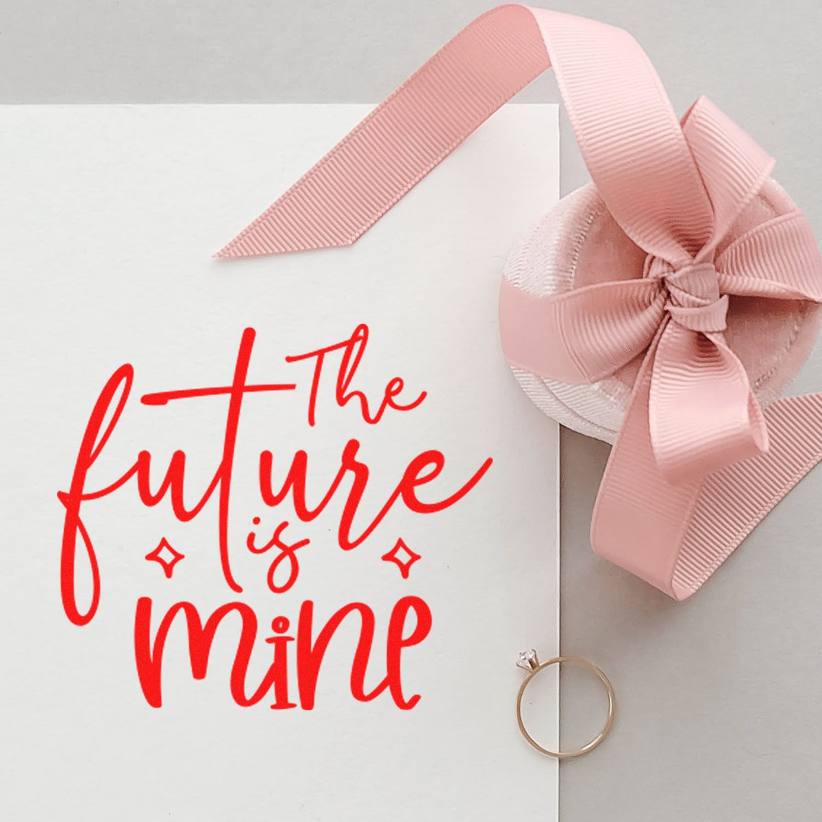 White stamp card with bright red the future is mine lettering, blush pink ribbon bow seal, and pink ribbon accent.