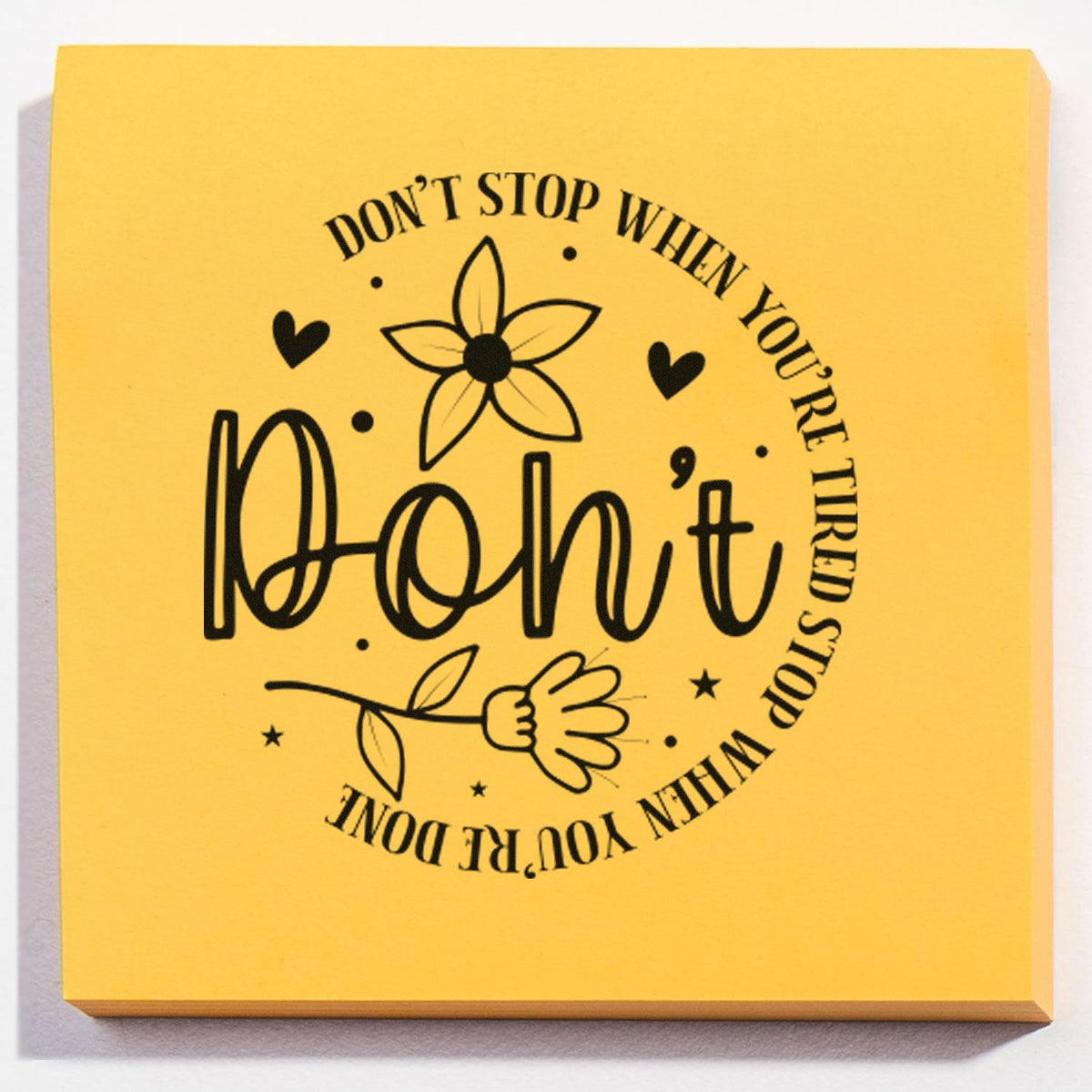 Yellow stamp and seal block with black floral design and motivational text, Don't stop when you're tired, stop when you're done.