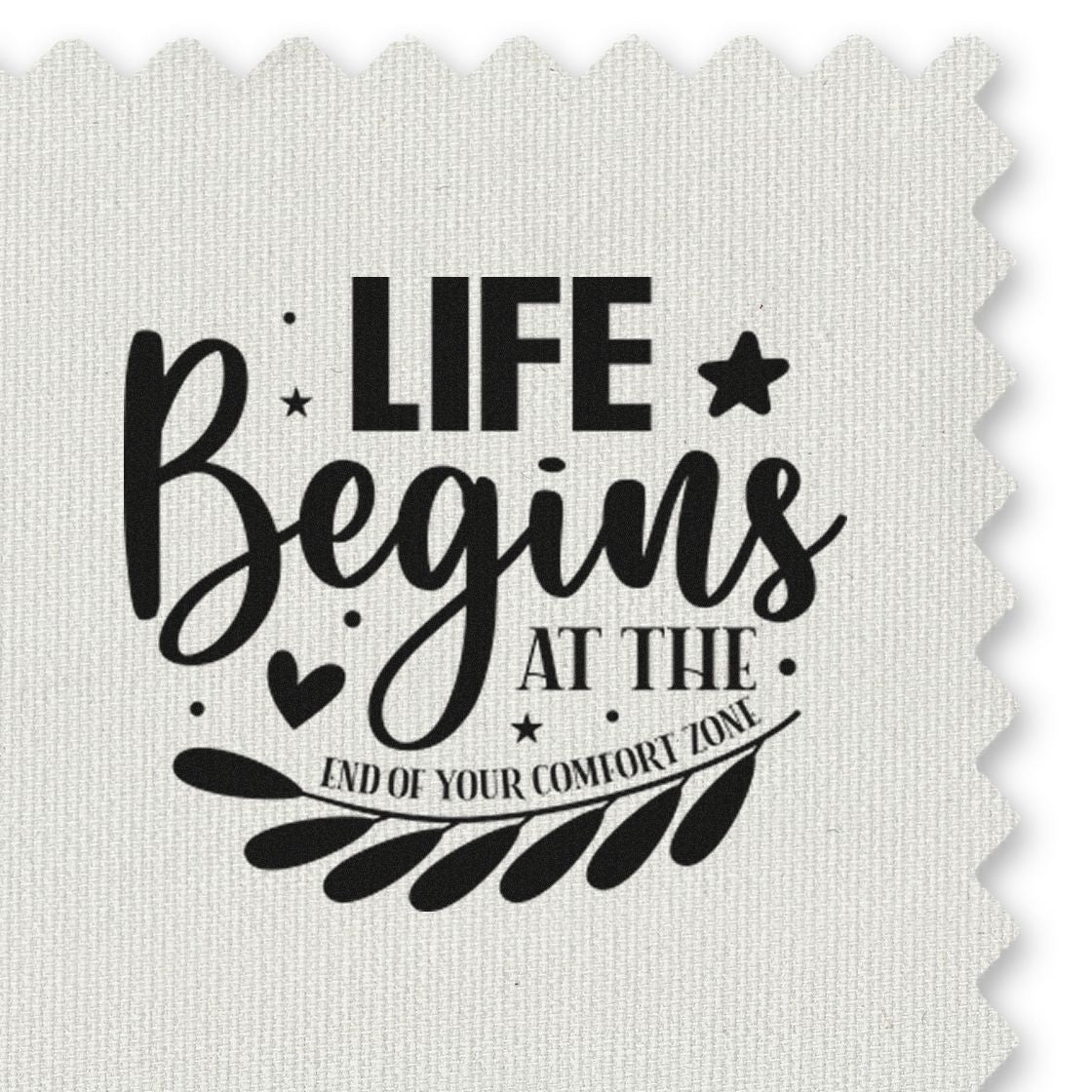 Black decorative stamp reading Life Begins at the End of Your Comfort Zone on white fabric, with stars, heart, and leaf motif.
