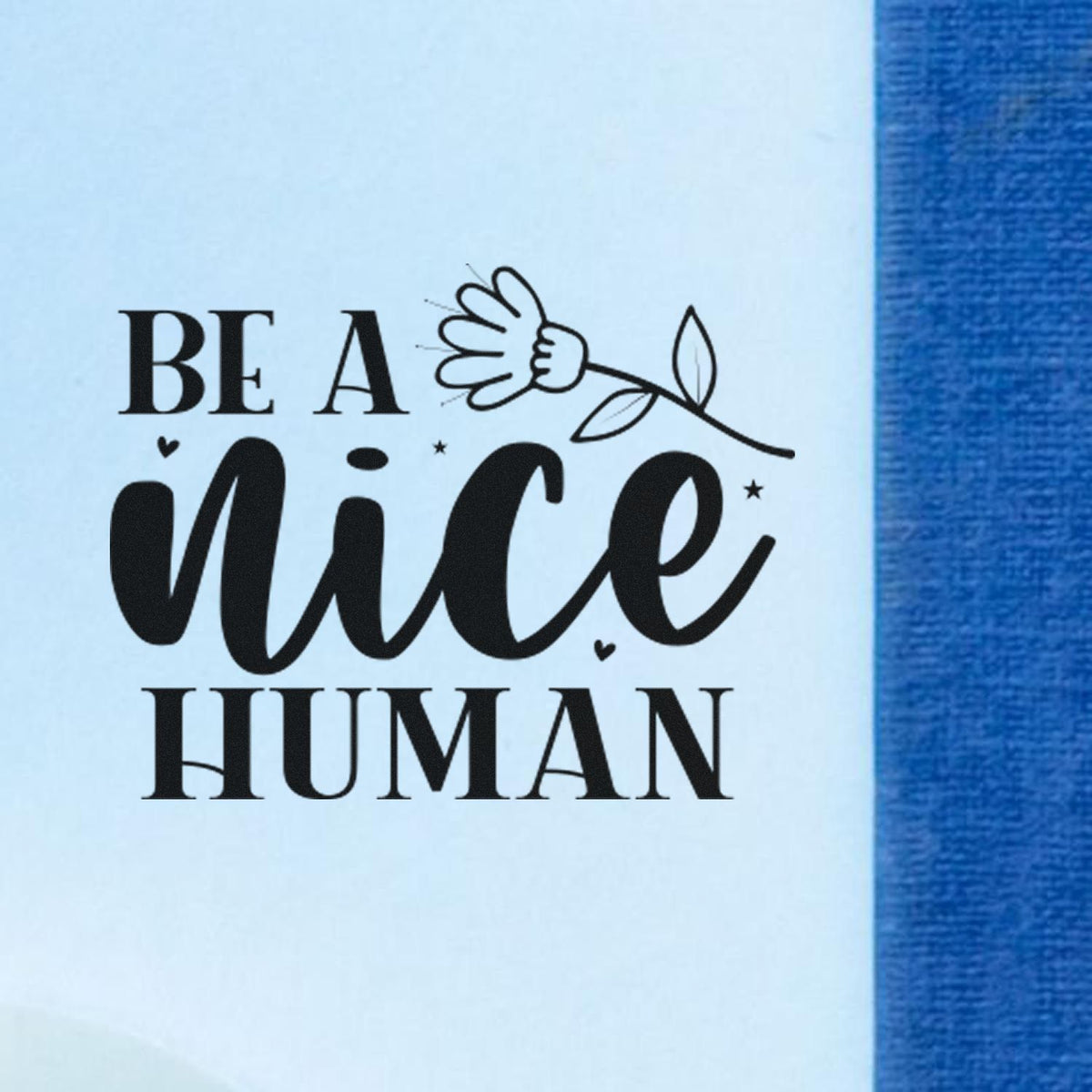 Black Be a Nice Human stamp and seal design with flower graphic on light blue background and blue edge.