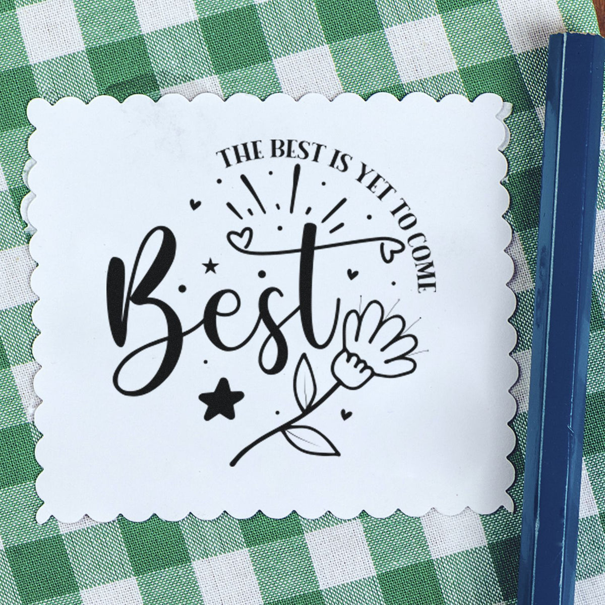 White scalloped seal sticker with black Best text and heart-and-flower design on green gingham, beside a blue stamp.