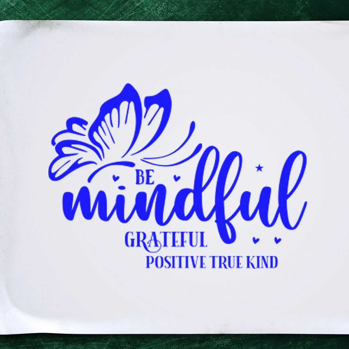 Blue rubber stamp seal with butterfly and Be mindful, grateful, positive, true, kind in blue on white paper.
