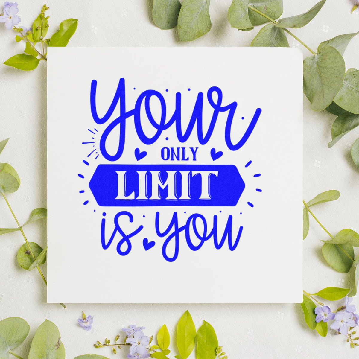 Blue custom stamp seal reading your only limit is you on a white card, framed by green leaves and purple flowers.