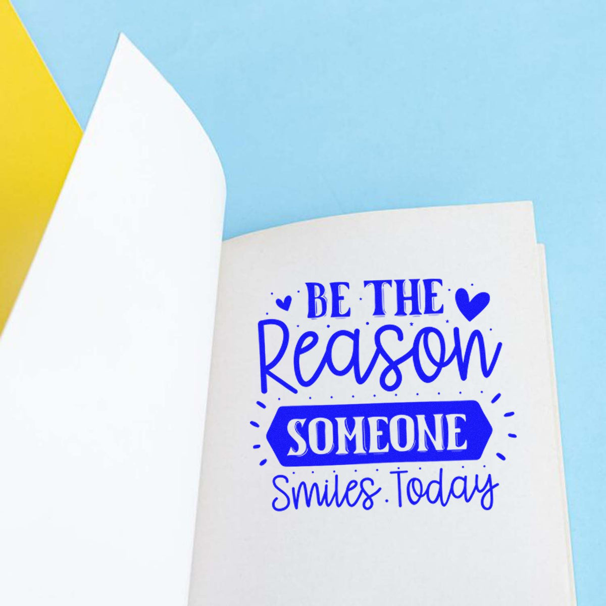 Blue custom stamp and seal design on white page: Be the Reason Someone Smiles Today with hearts on a light blue background.