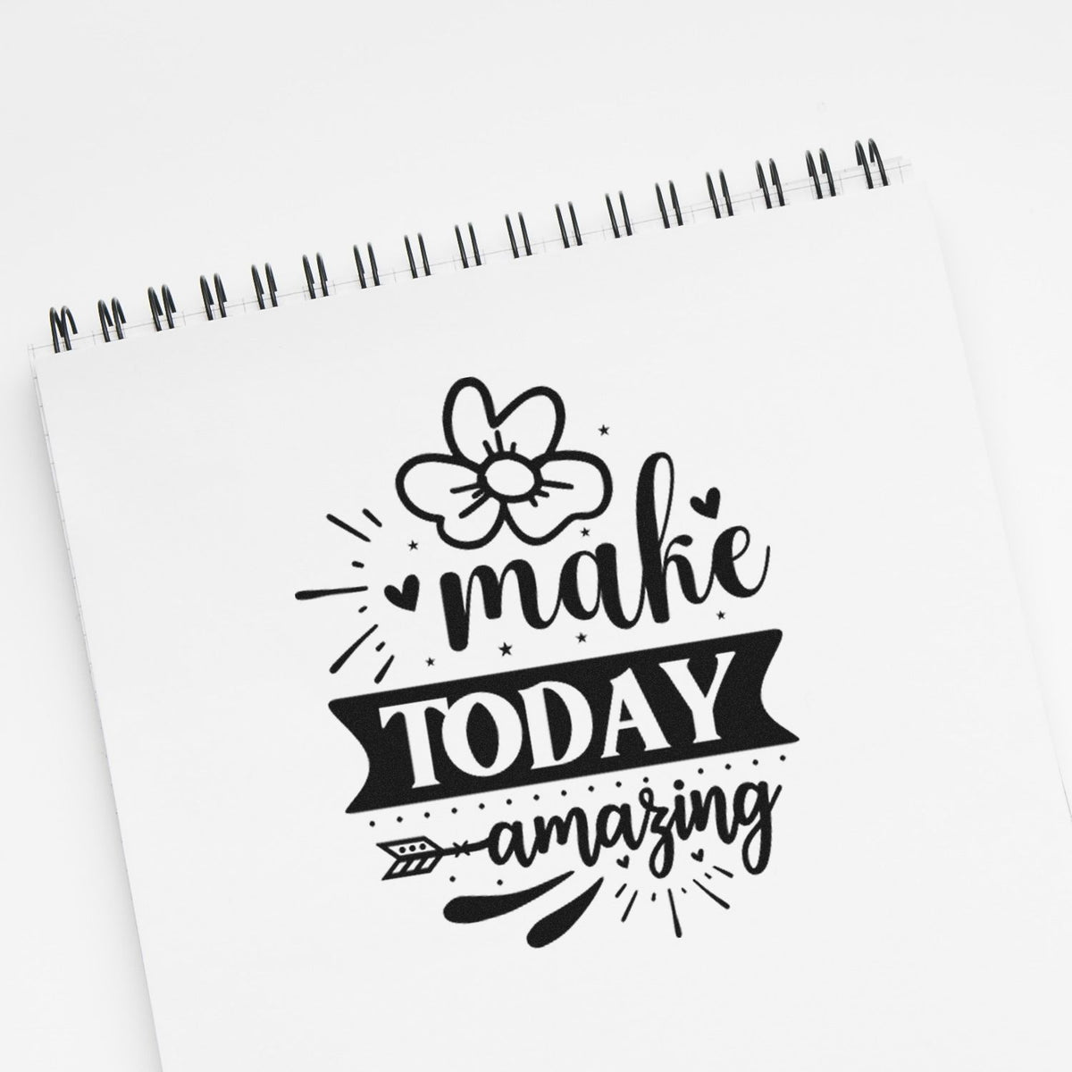 Black stamp/seal design on a white spiral notebook with flower, hearts, and make TODAY amazing text.
